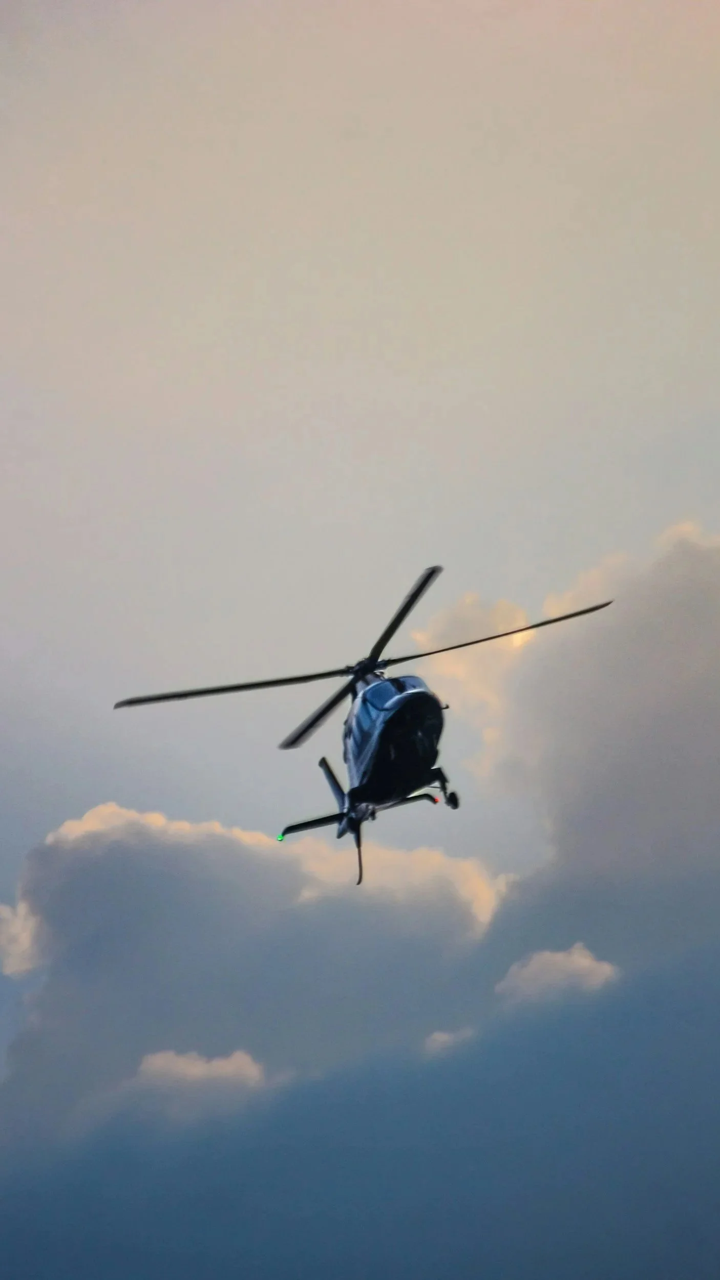 A helicopter flying in the sky with clouds at dusk.