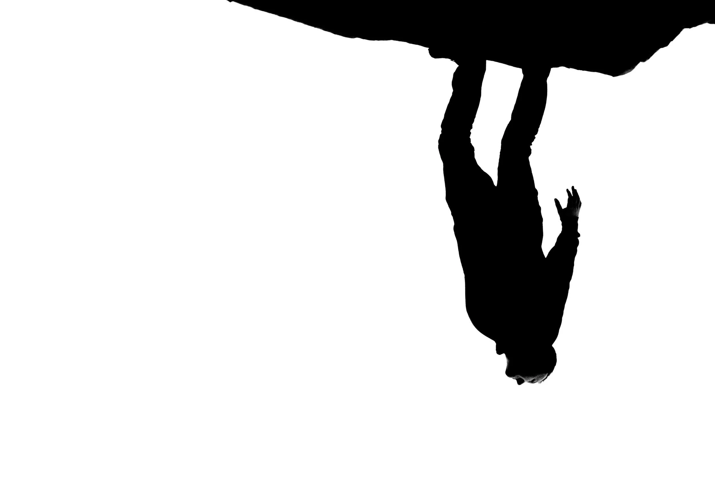 Silhouette of a woman with long hair, standing and holding her hand up to her face, viewed from the side.