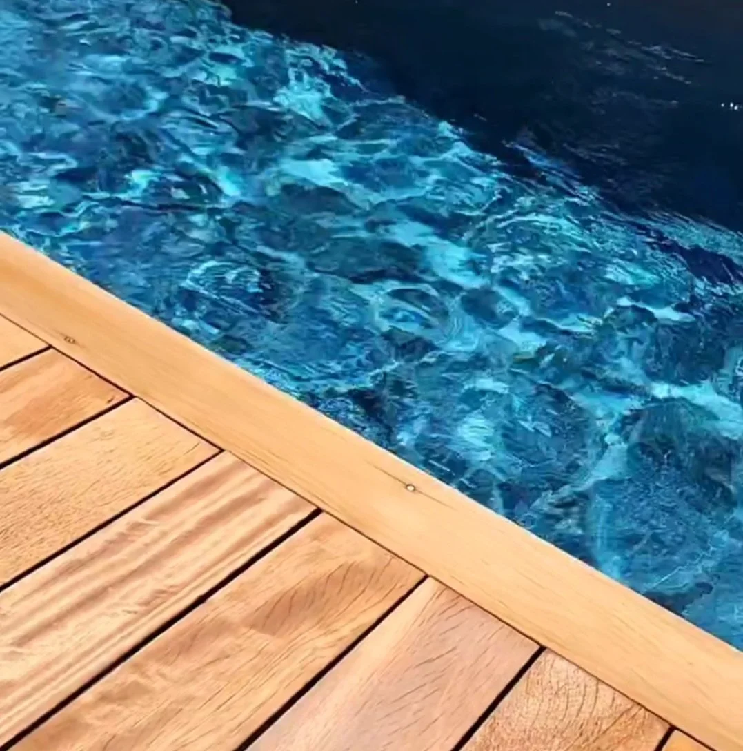 Bord en bois à proximité d'une piscine bleue.