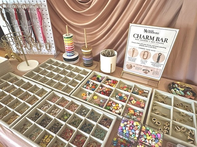 A curated charm bar with jewelry trays, decorative charms, and supplies to make key chains.