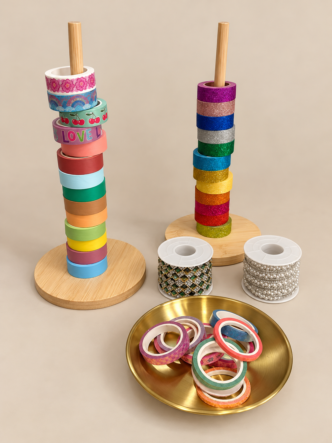 Colorful rolls of decorative tape stacked on wooden bases and in a gold dish, with additional rolls of embellishments in silver and green in front.