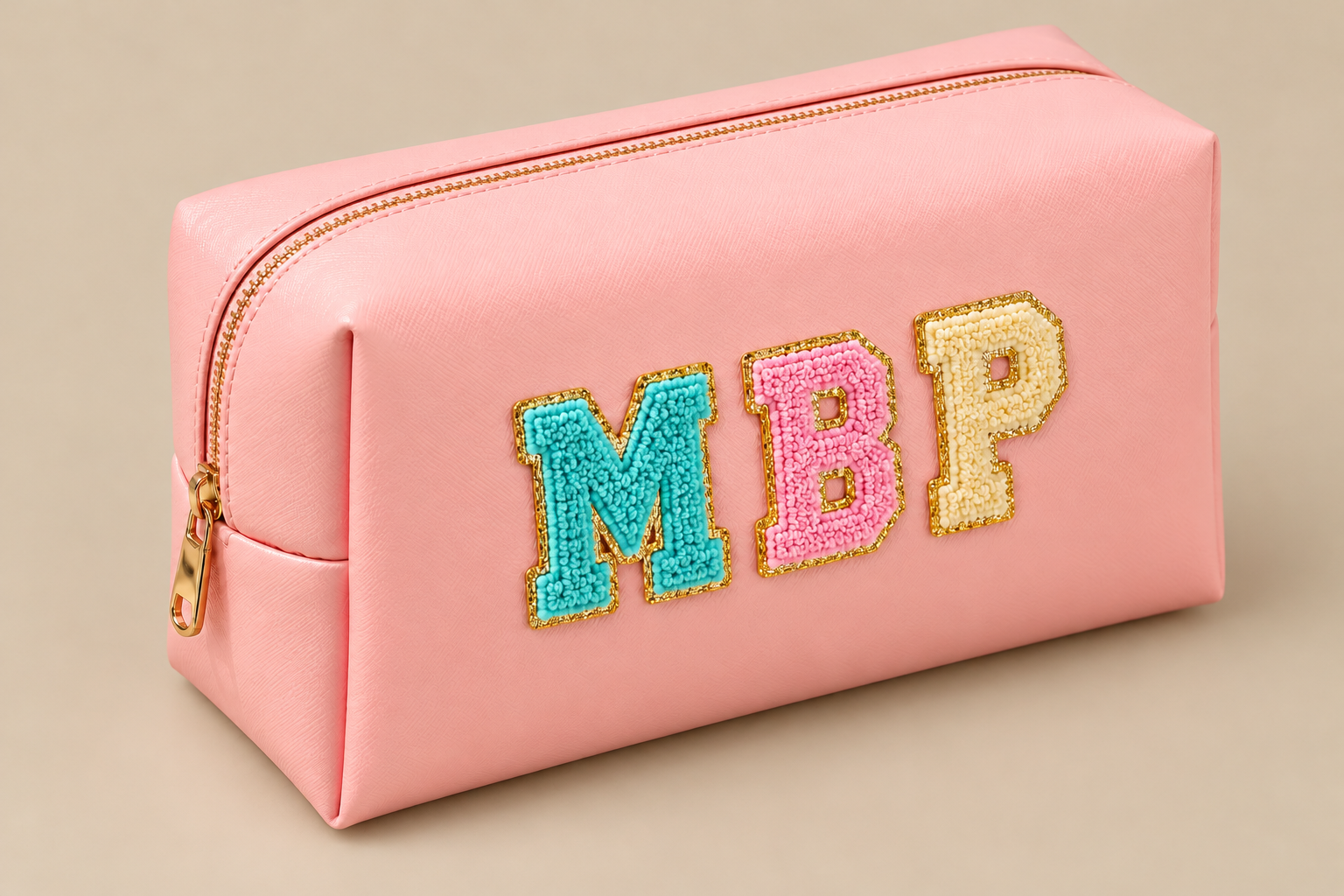 Pink bag with embroidered letters 'MBP' in blue, pink, and yellow with gold trim.