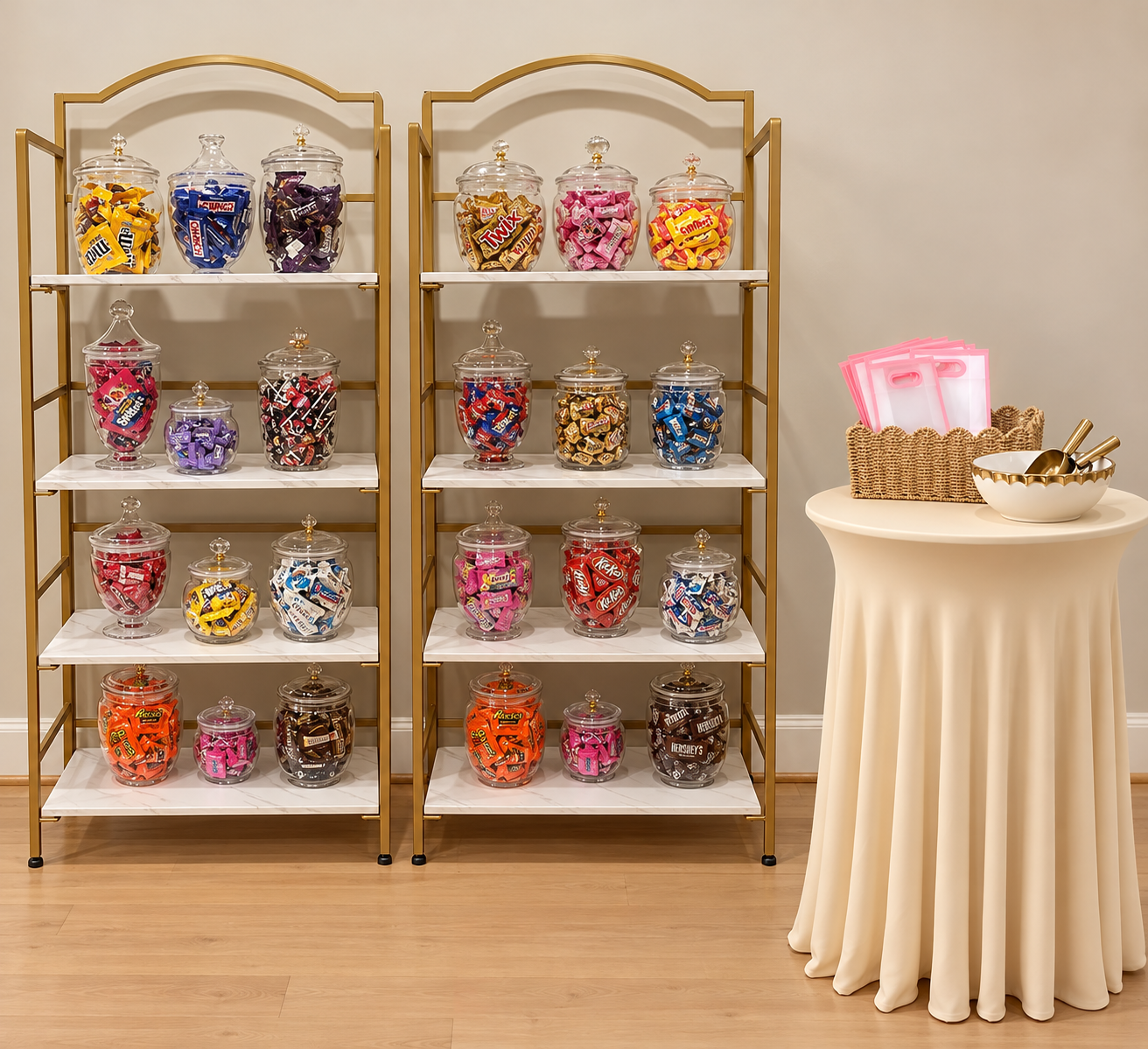 Candy jars filled with assorted wrapped candies on white and gold shelves, next to a table with pink bags and bowls with scoops for serving.