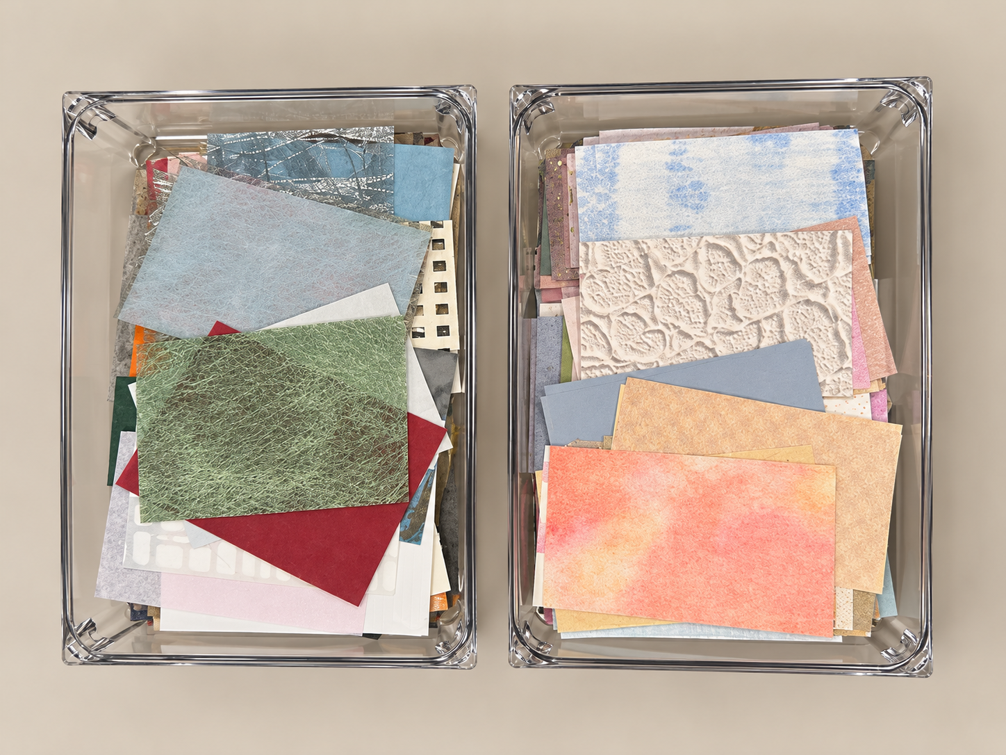 Two clear plastic boxes filled with colorful paper and fabric scraps on a beige surface.