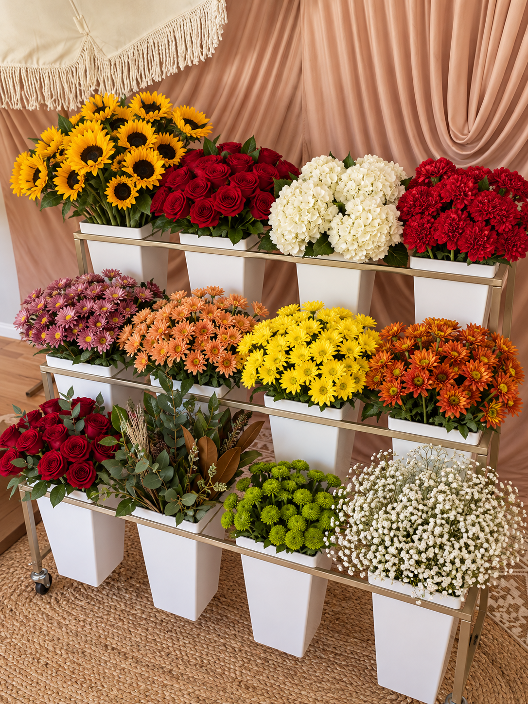 A mobile flower bar featuring seasonal blooms displayed in white buckets on a gold tiered cart.