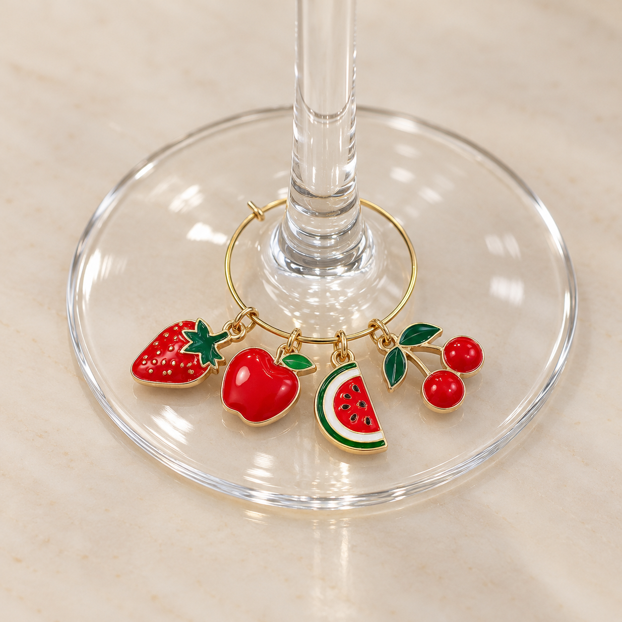 A gold bracelet with colorful fruit-shaped charms including a strawberry, apple, watermelon slice, and cherries, placed on a glass stand on a light-colored surface.