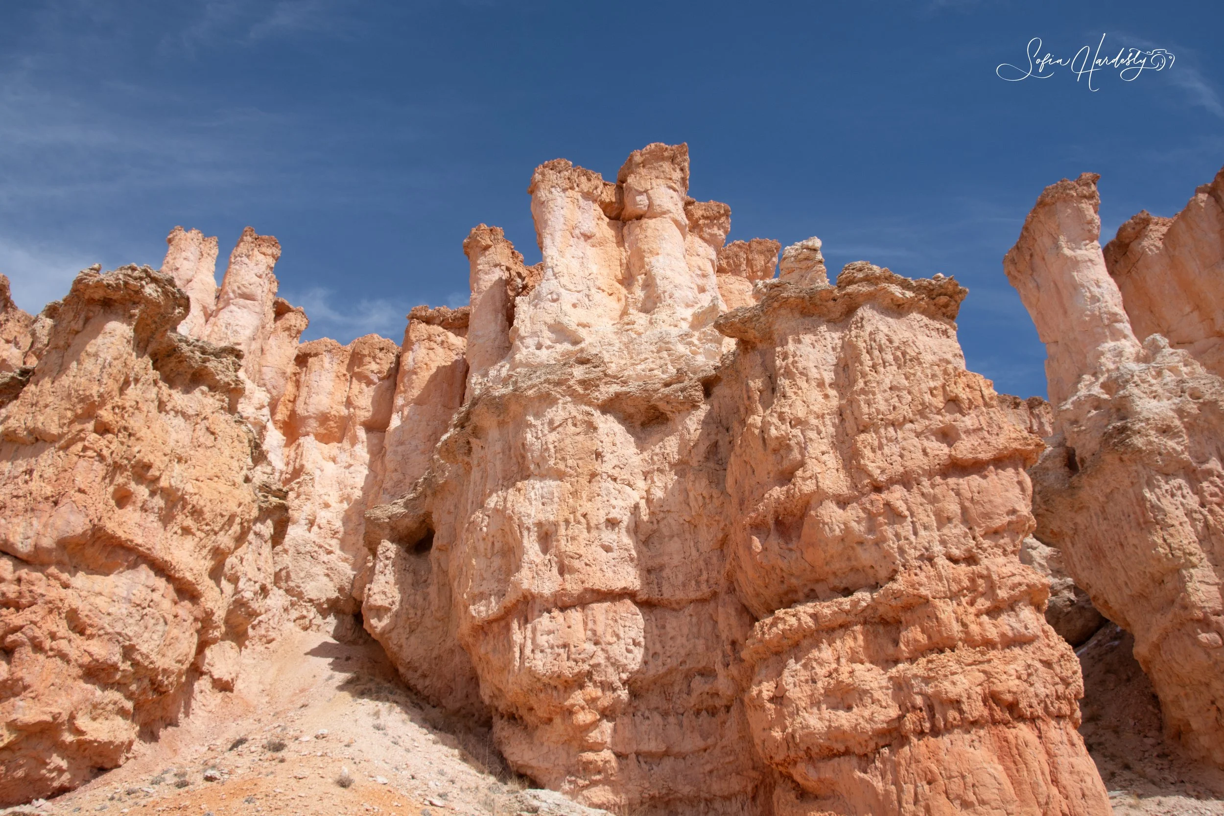 Pink and beige rocky formations under a clear blue sky.