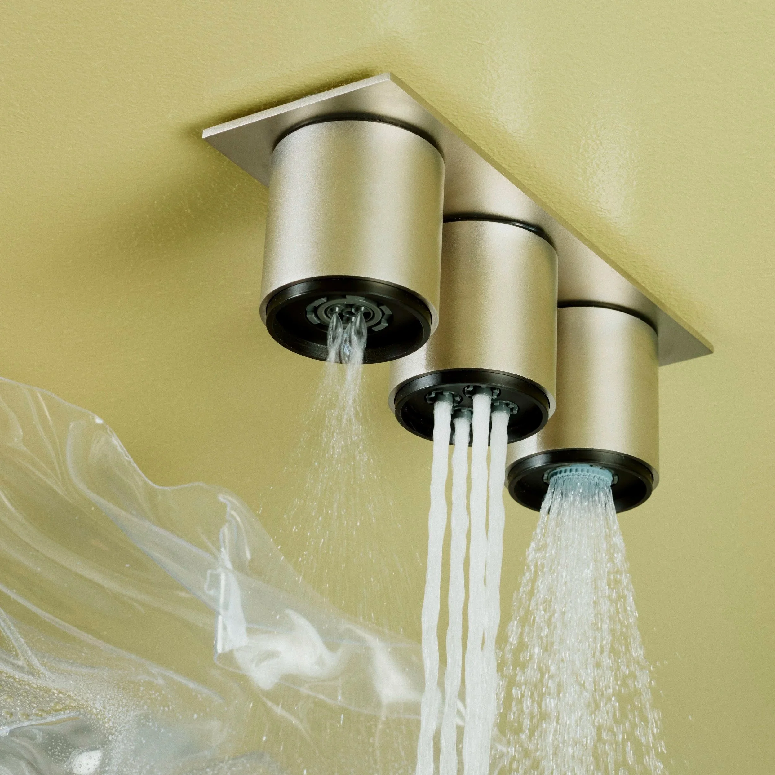 Close-up of a stainless steel showerhead with water flowing from multiple nozzles.