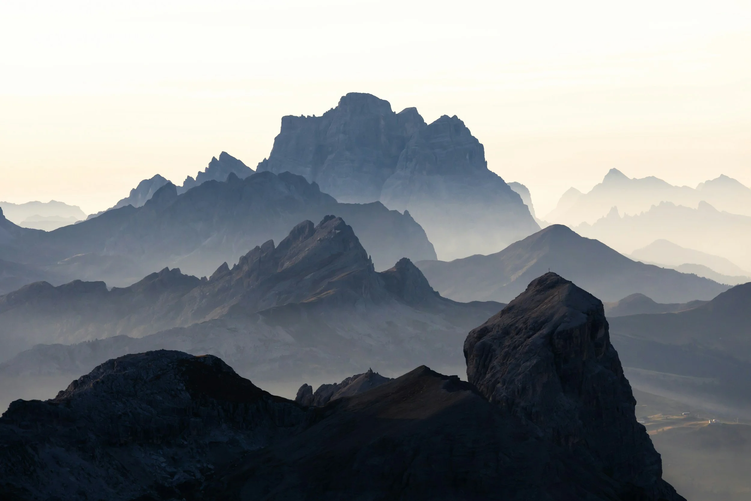 A panoramic view of multiple rocky mountain peaks, shrouded in mist and fog, sacred and serene energy