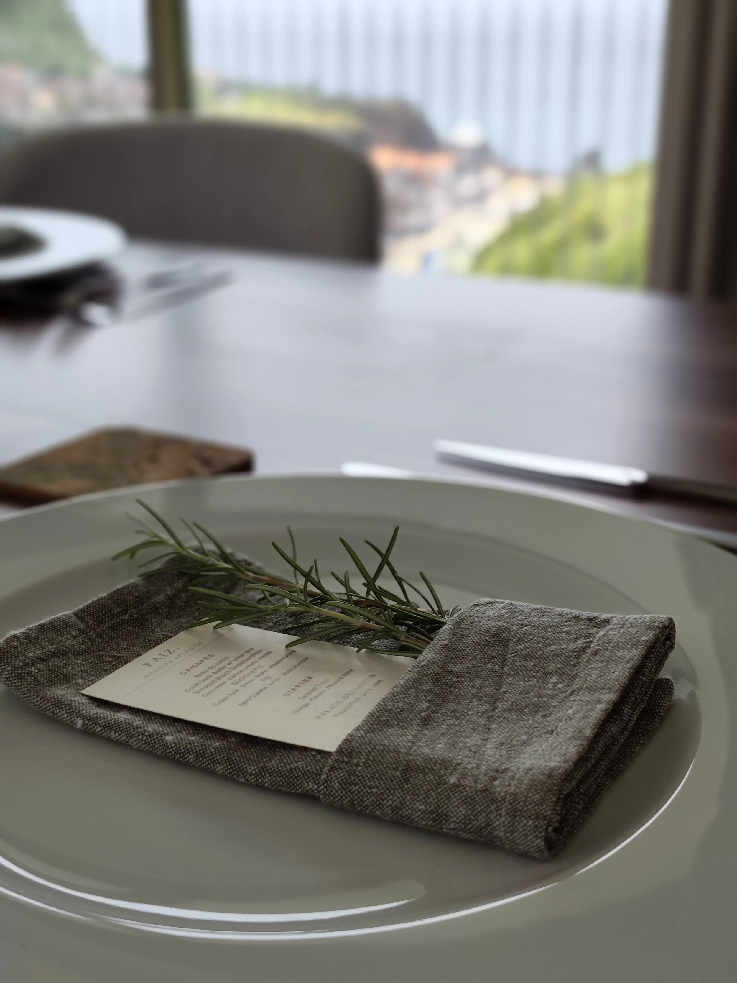Place setting with linen napkin, menu card and rosemary