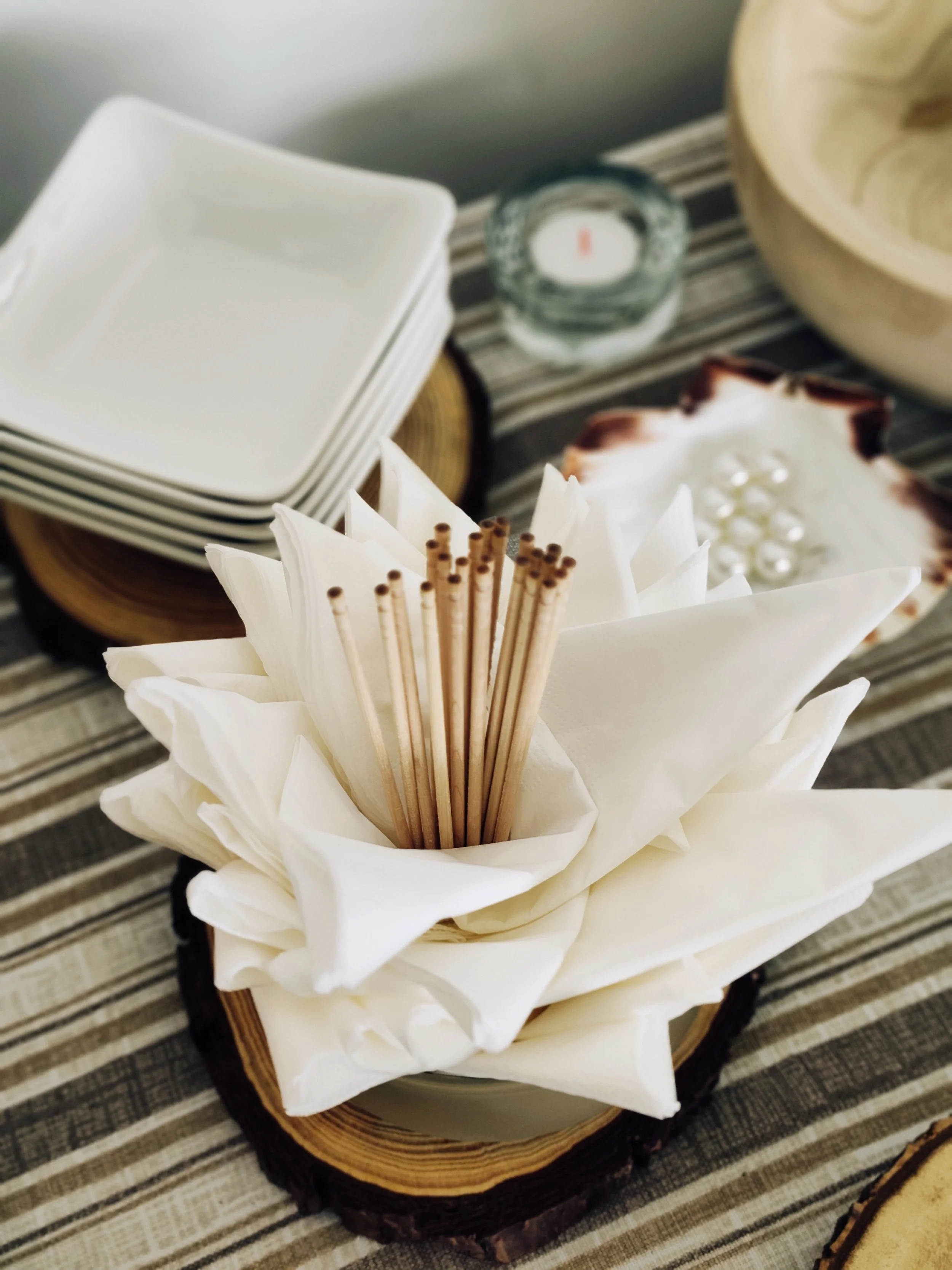 Table service detail with folded napkins, wooden picks and decorative elements