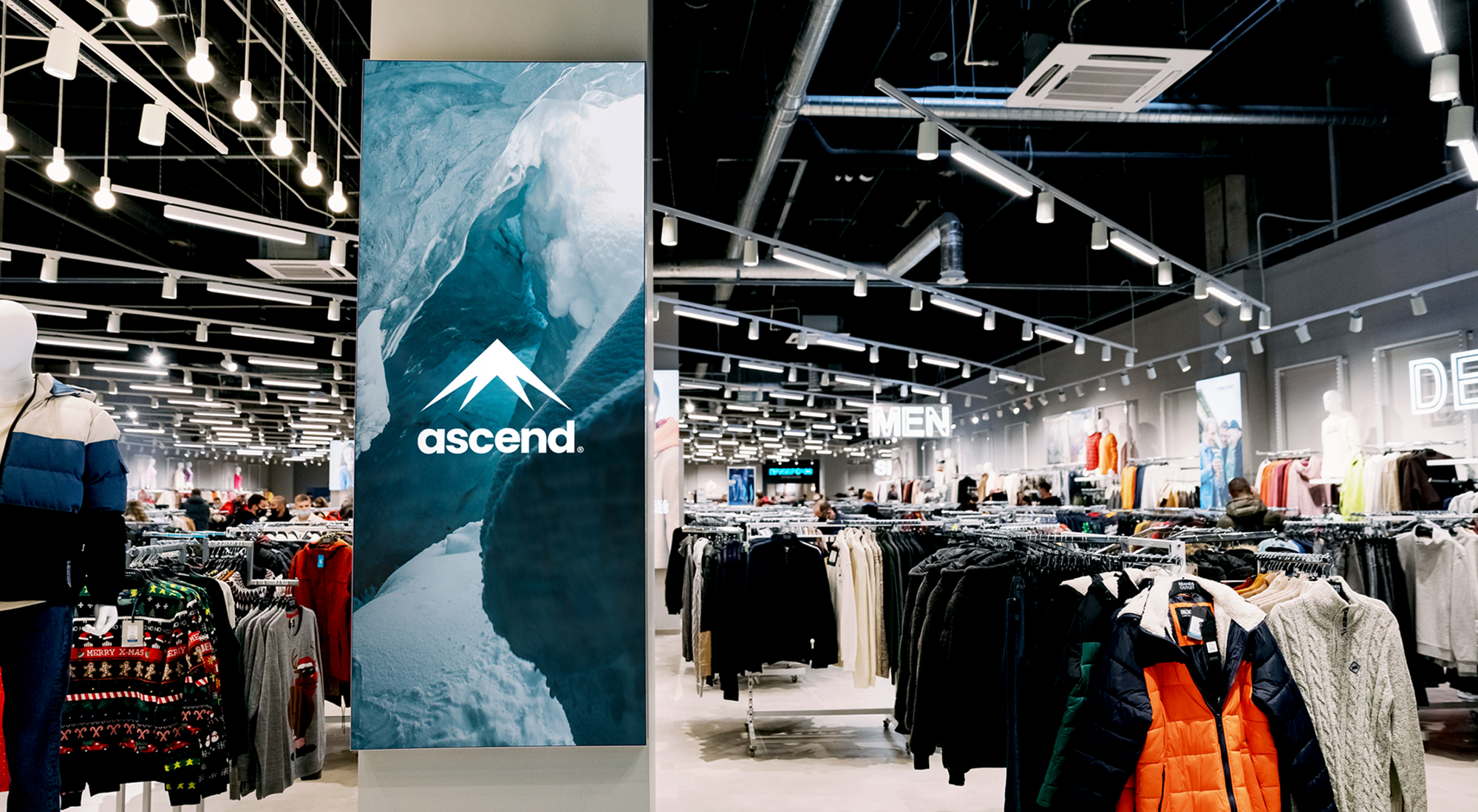 Ascend clothing store interior with racks of apparel, mannequins, shoppers, and a prominent ice-themed Ascend sign