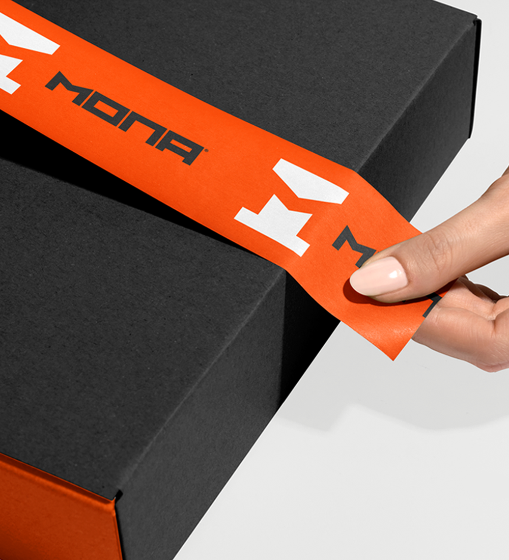 Close-up of a hand peeling an orange branded seal from a black box