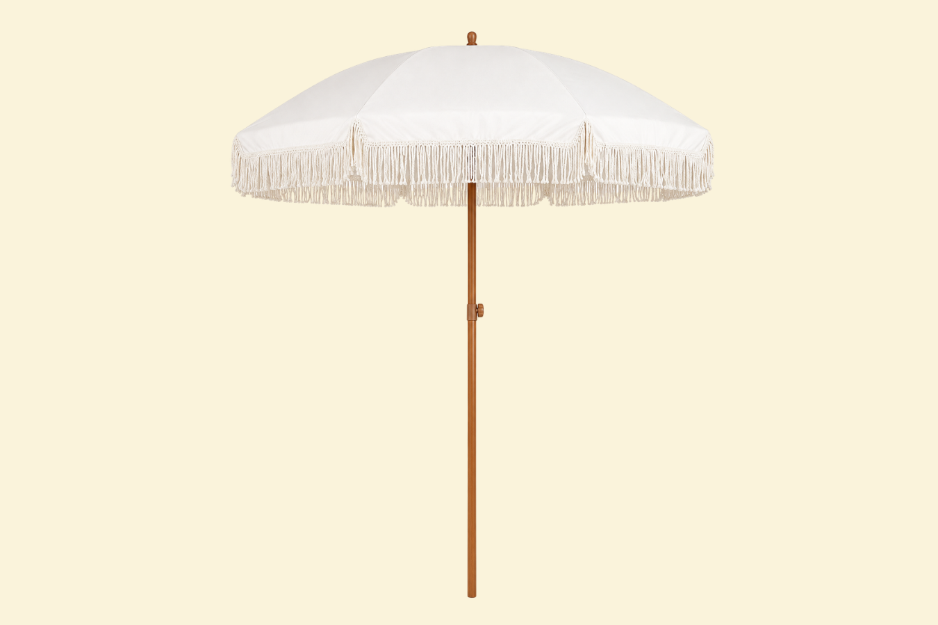White beach umbrella with decorative fringe and wooden pole against a light background.