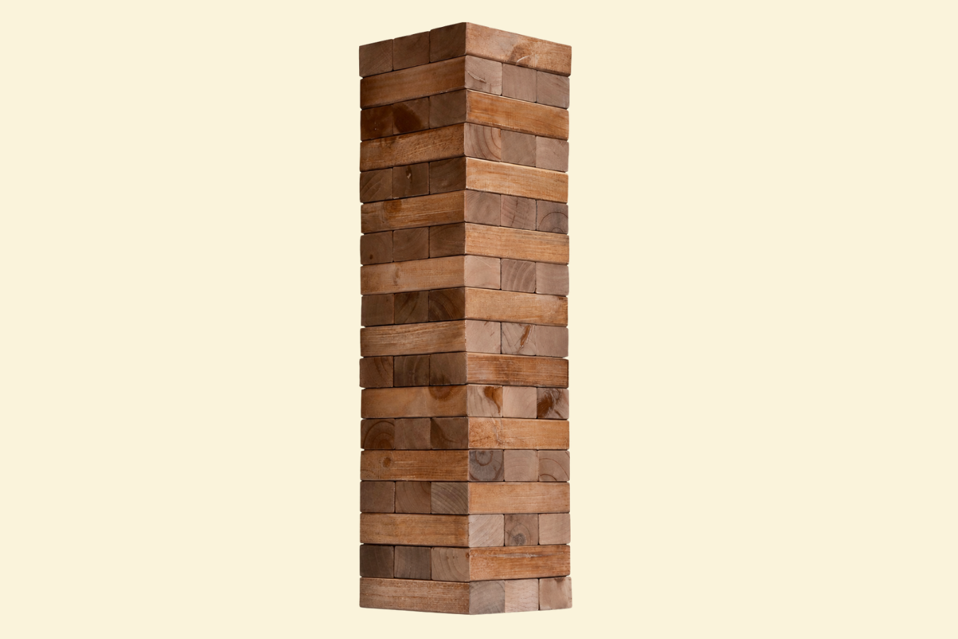 A tall Jenga tower made of wooden blocks against a plain beige background.
