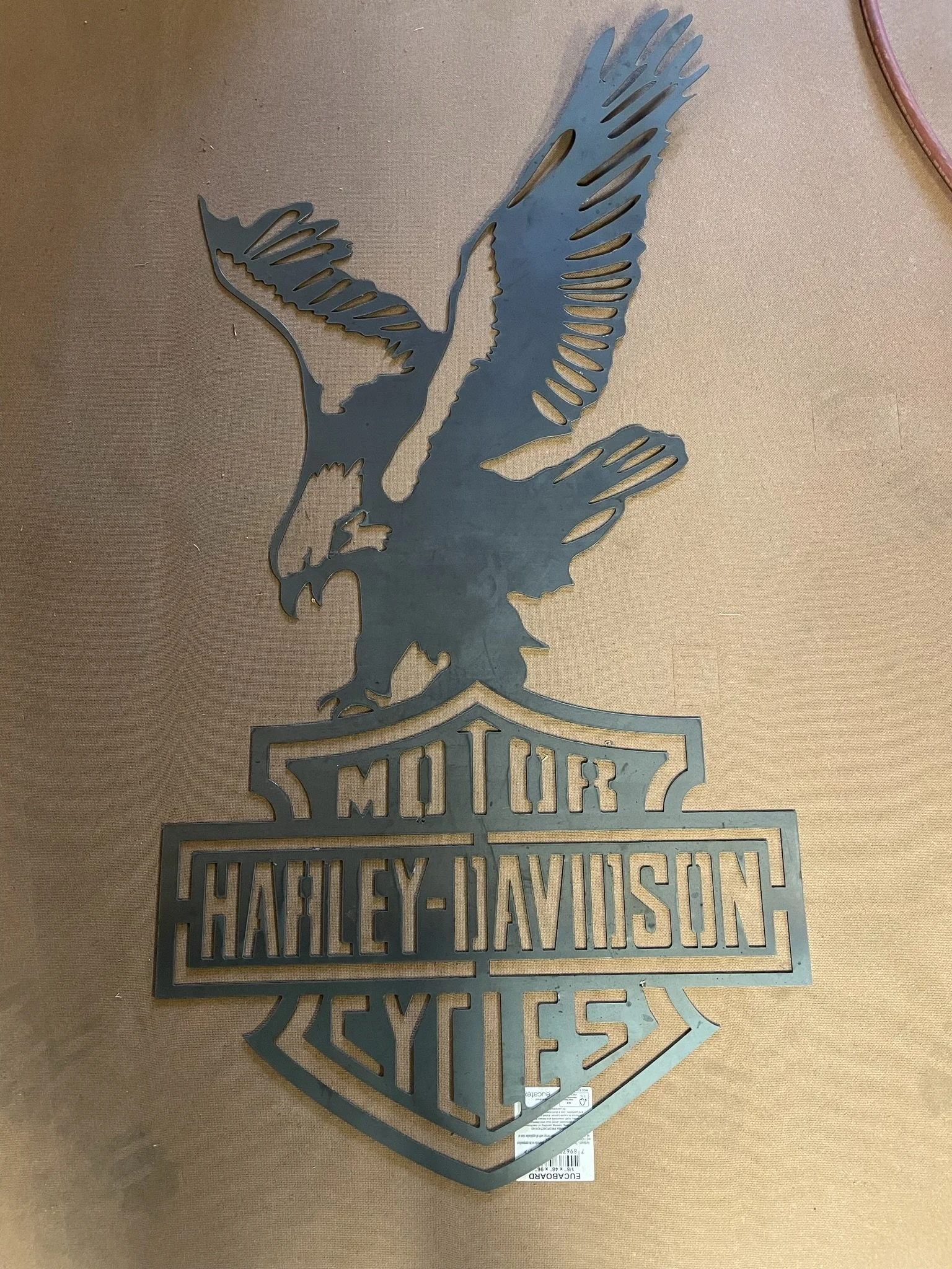 Metal Harley-Davidson motorcycle dealership sign with eagle and shield design.