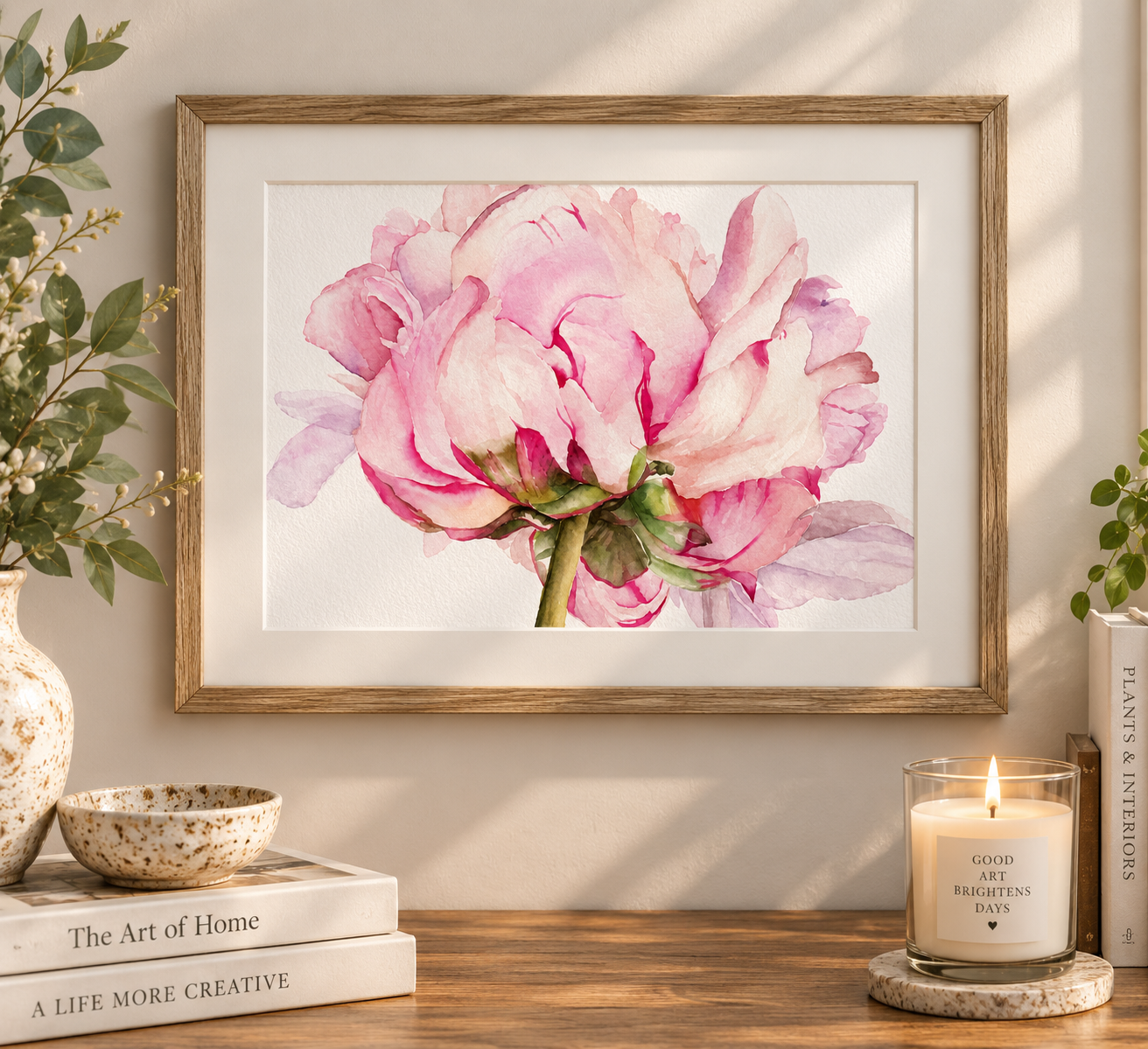 Pink peony watercolor print displayed in a natural wood frame with an ivory mat on a softly lit neutral wall.