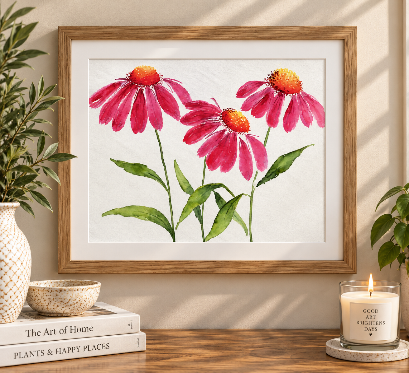 Pink coneflower watercolor print displayed in a natural wood frame with a white mat on a warm neutral wall, styled with plants and cozy home décor.