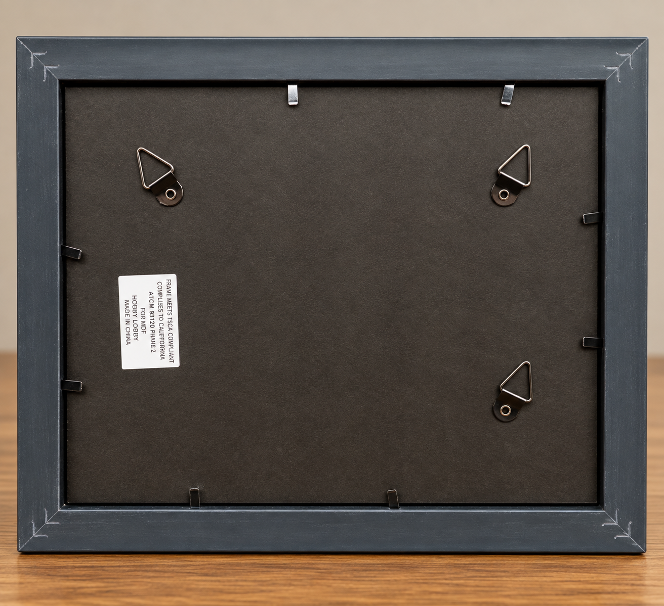 Back of the Quiet Bloom 8x10 black frame showing the dark backing, frame fasteners, and metal hanging hardware.
