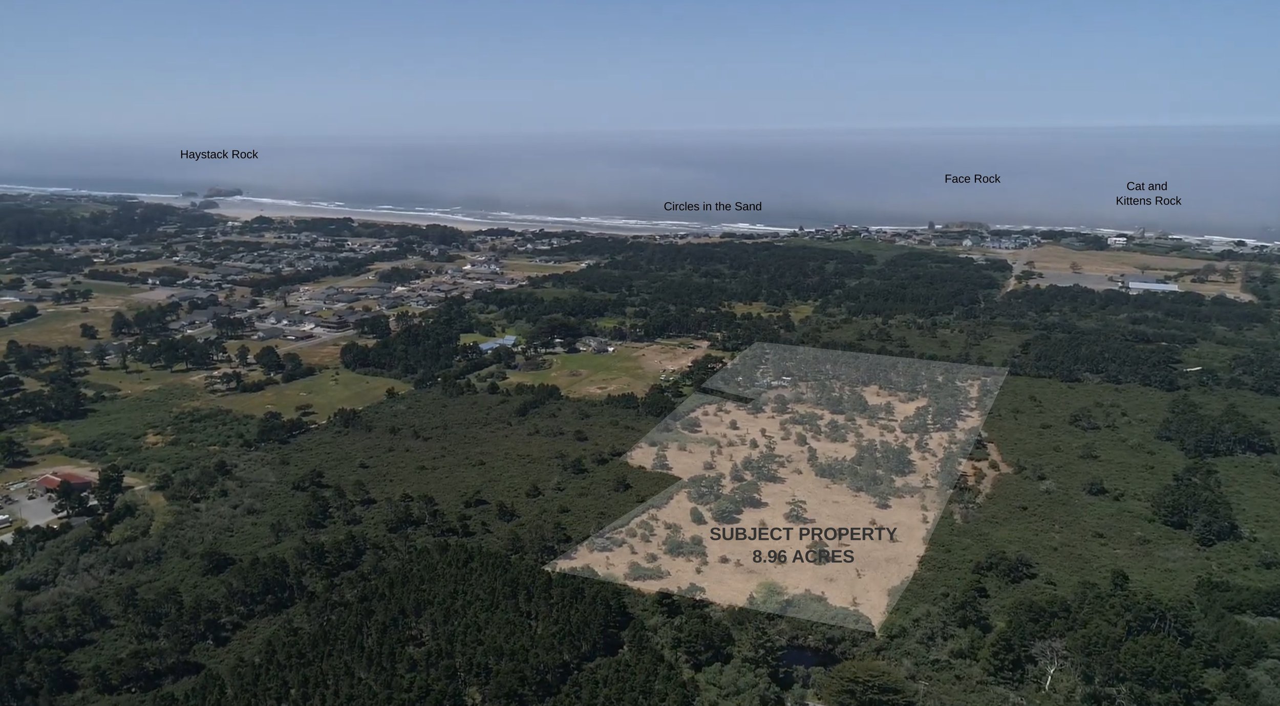 Drone aerial view of the cleared 8.96-acre Face Rock Heights property in west Bandon, Oregon, looking toward the Pacific Ocean and nearby coastal neighborhoods.