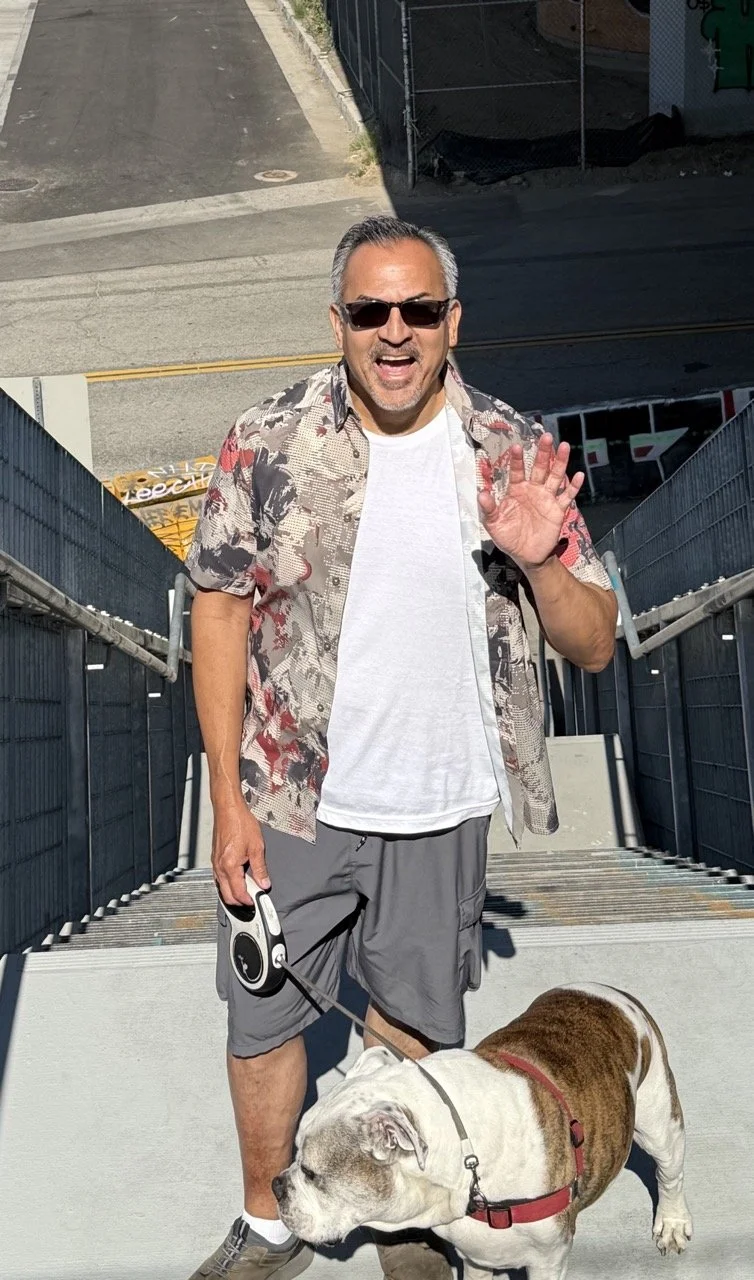 Joe Garcia waves and smiles in downtown Los Angeles. His best buddy, Winston, could care less.