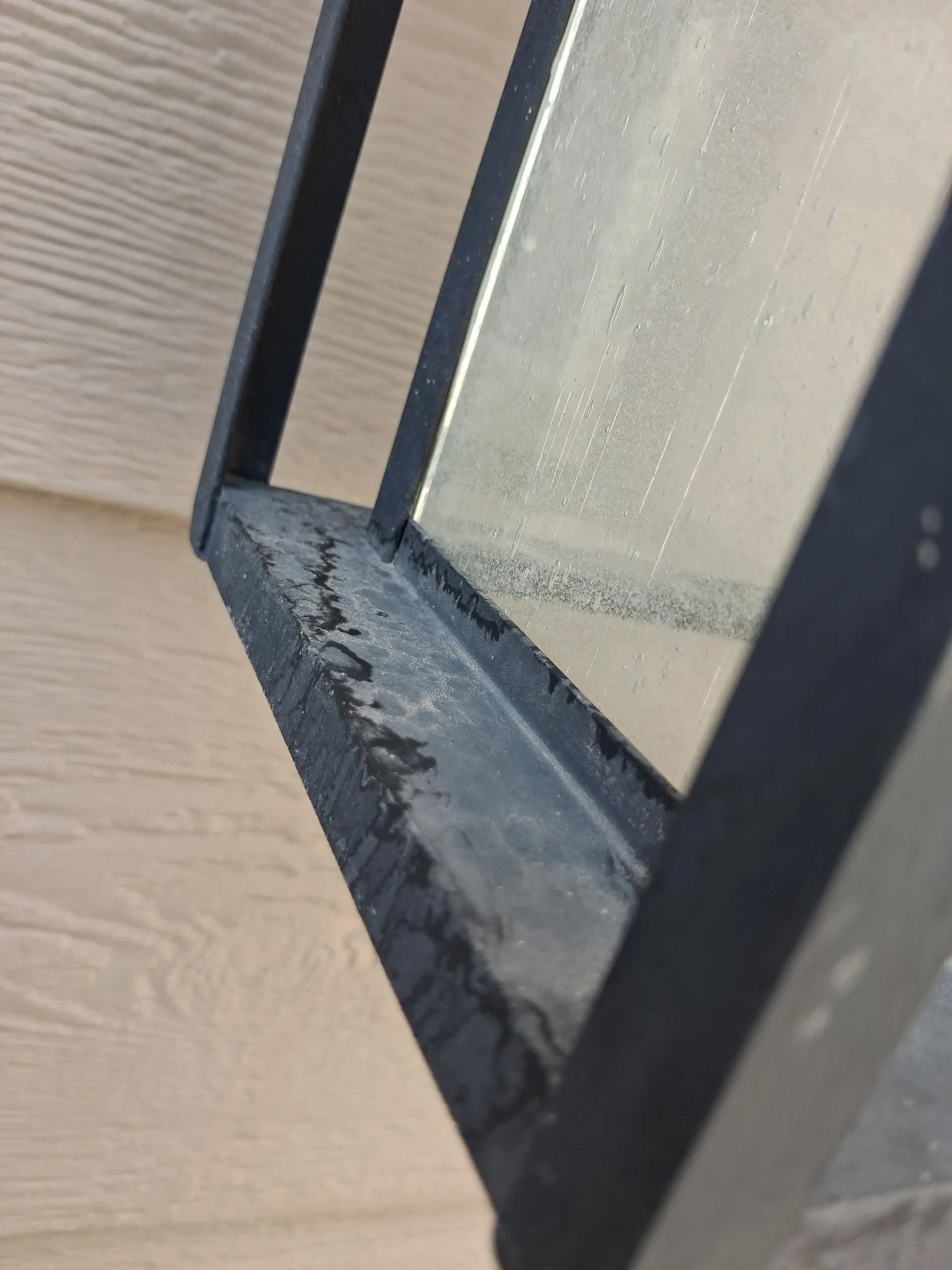 Exterior light fixture before professional cleaning by Reflect Window Cleaning (RWC), showing water spots and residue on the glass and metal surfaces.