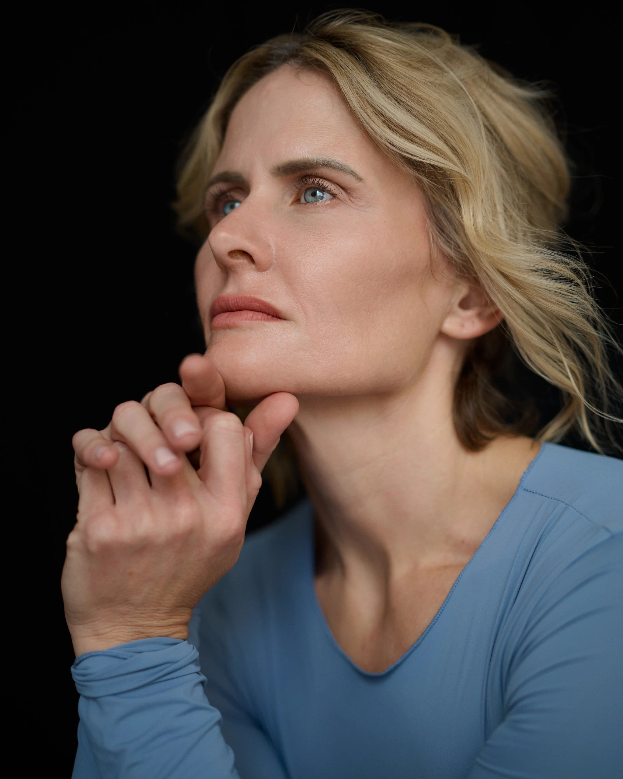 Close-up portrait of Christine Kiefer in a powder-blue outfit against a black background