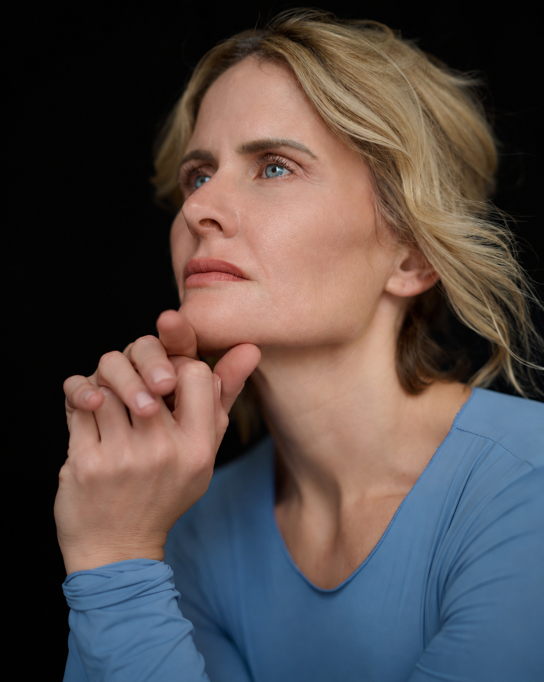 Close-up portrait of Christine Kiefer in a powder-blue outfit against a black background