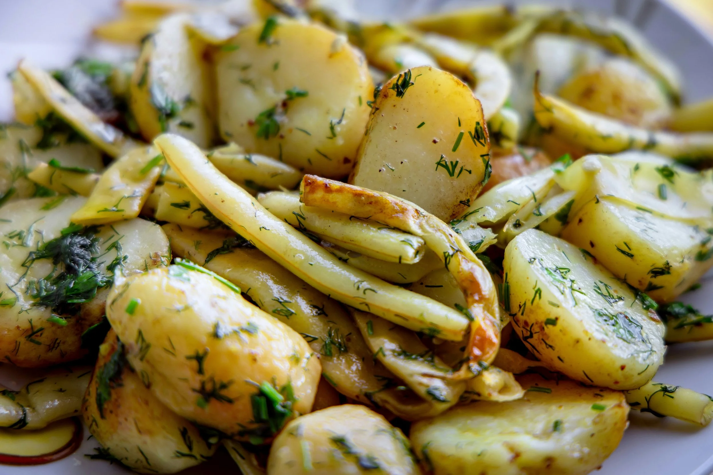 Close-up of roasted potatoes garnished with chopped herbs, likely parsley or dill.