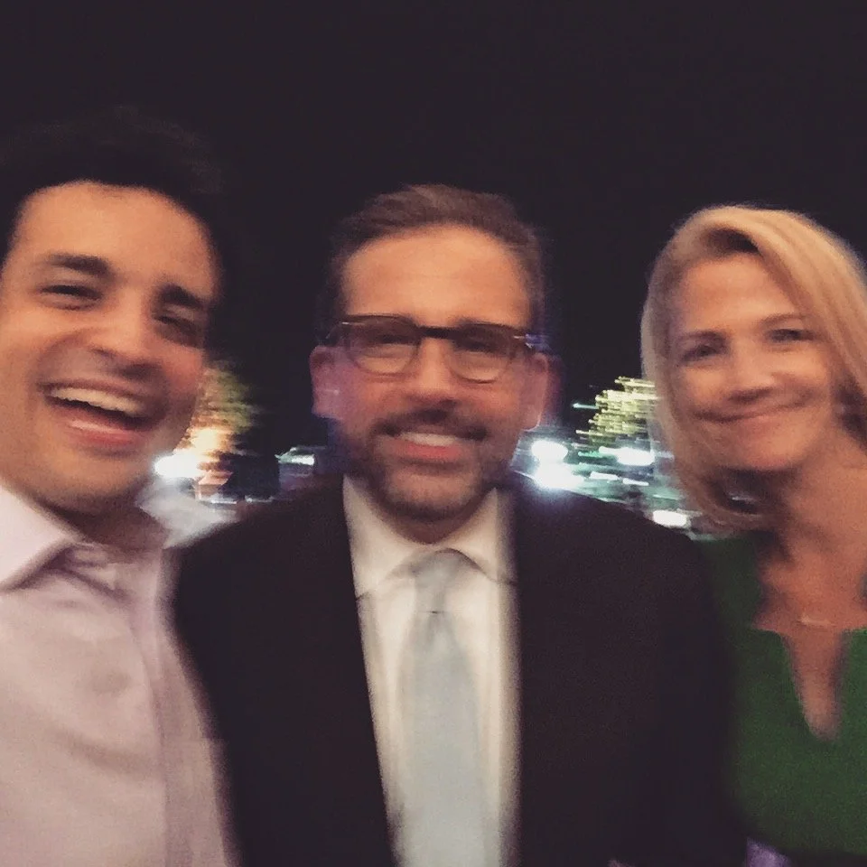 Three smiling people, two men and one woman, taking a selfie outdoors at night.