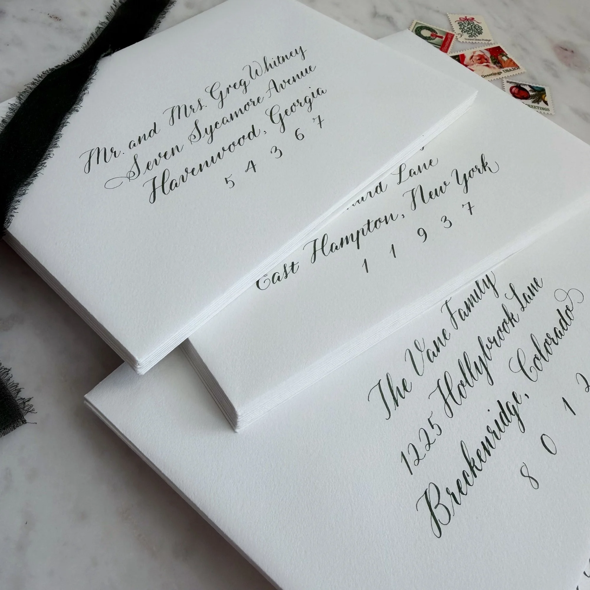 Christmas card envelope calligraphy in green ink on white paper