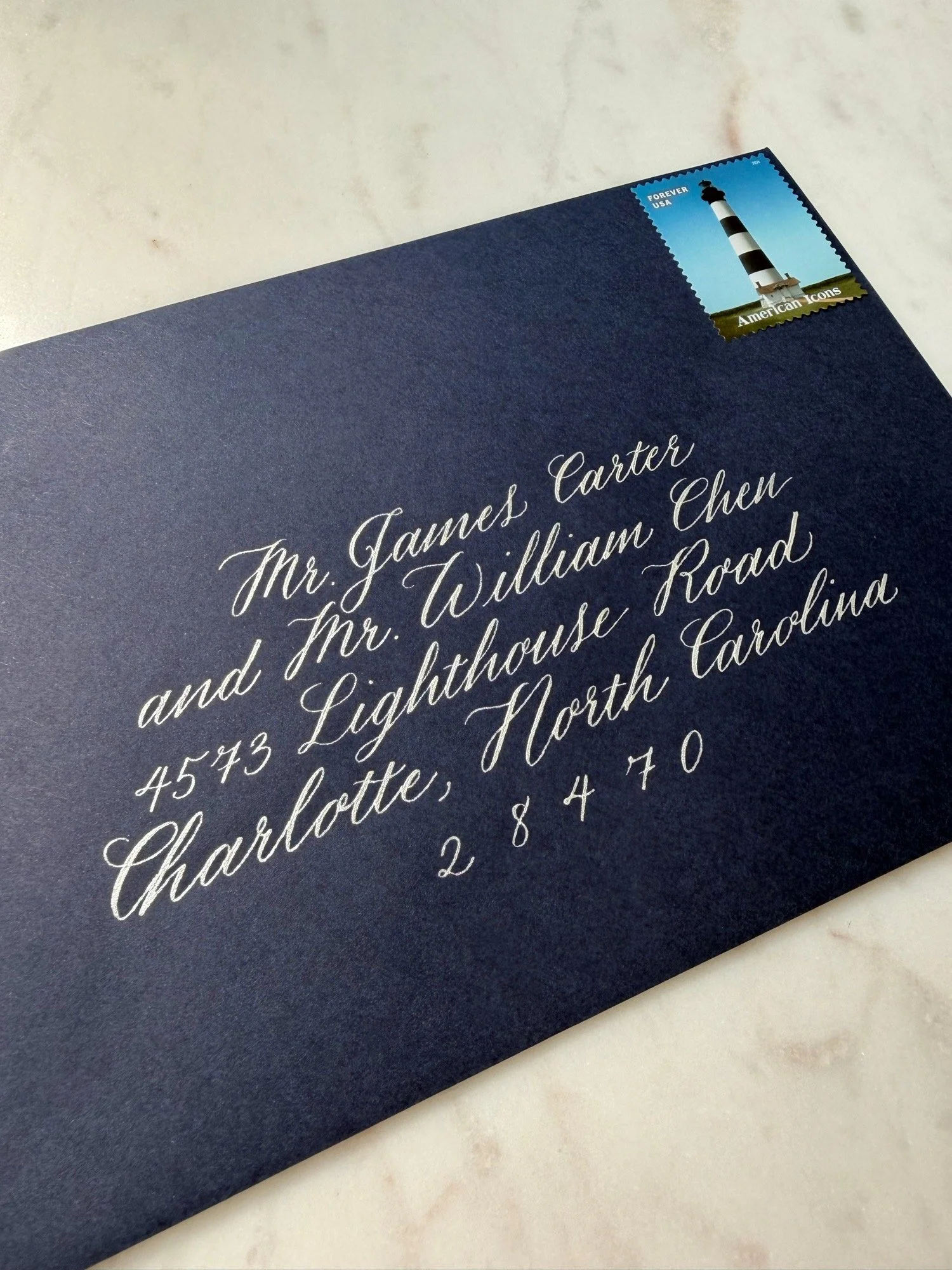 Navy blue envelope with modern script calligraphy in silver ink
