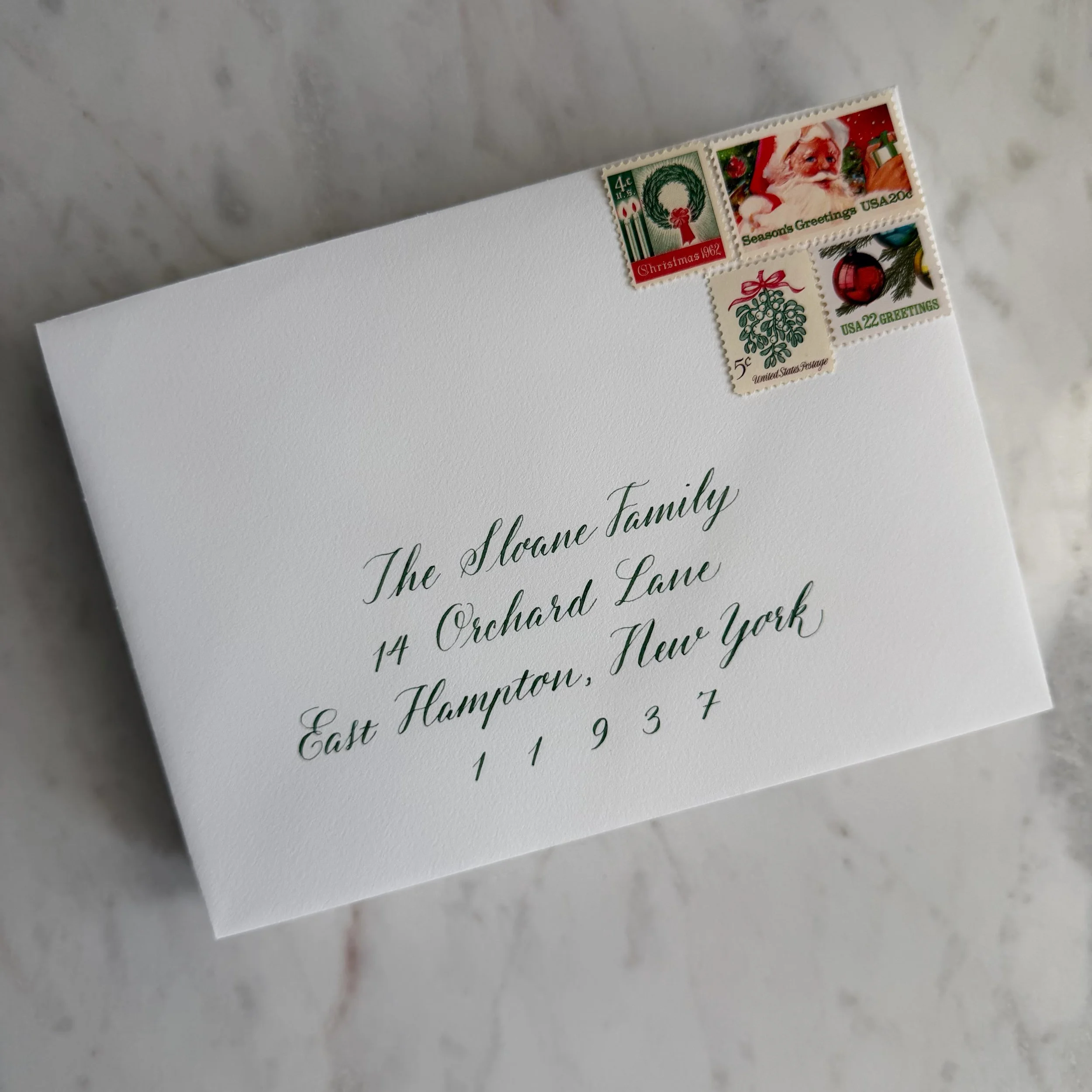 Christmas card envelope calligraphy in green ink on white paper