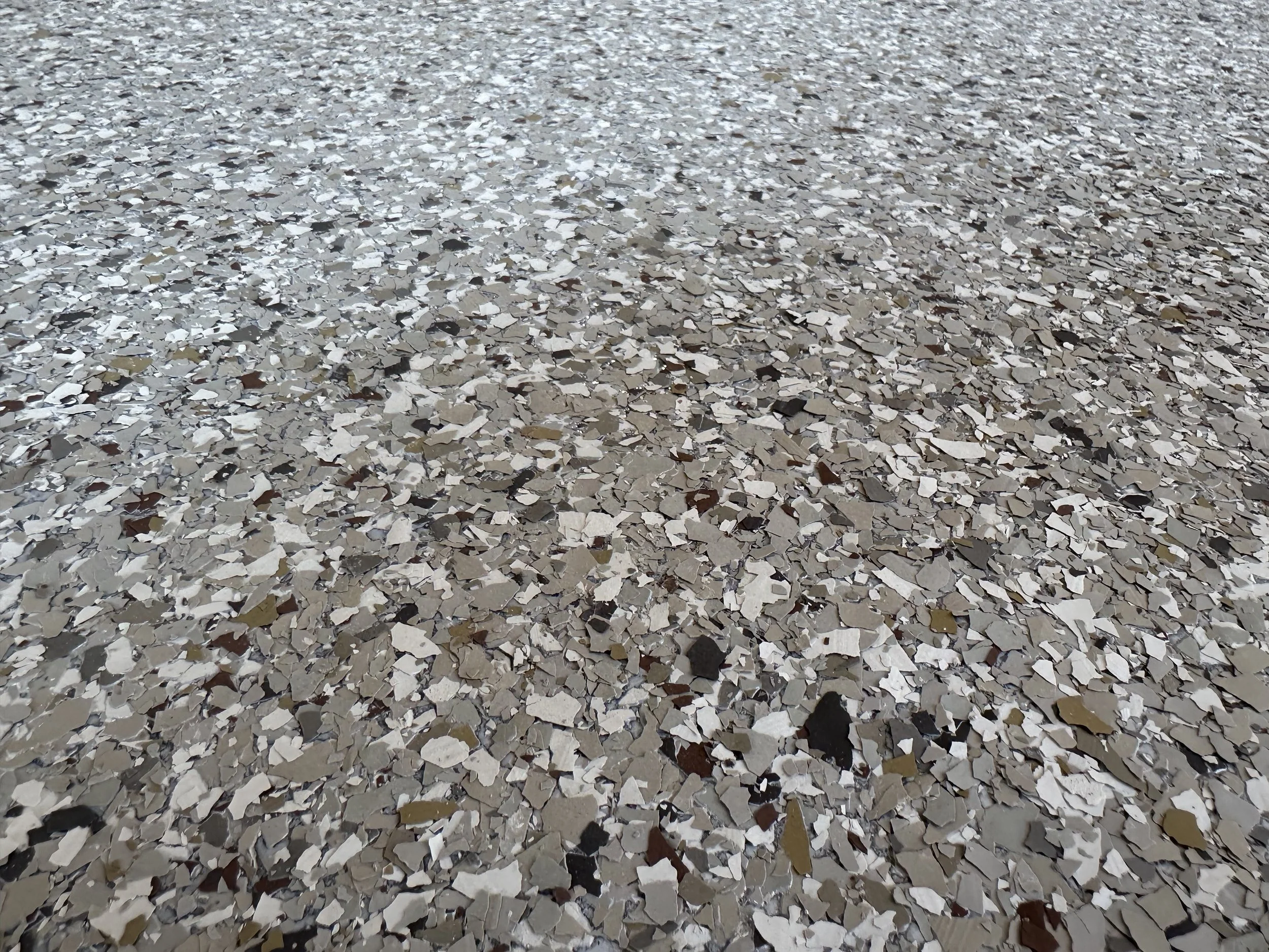 A close-up view of a floor covered in small, irregularly shaped broken mirror pieces reflecting light.