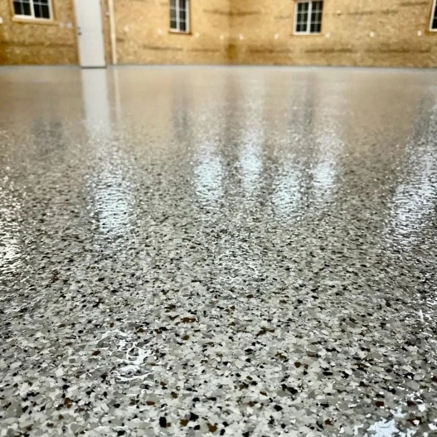 Close-up of a polished gray terrazzo floor with a building wall and windows in the background.