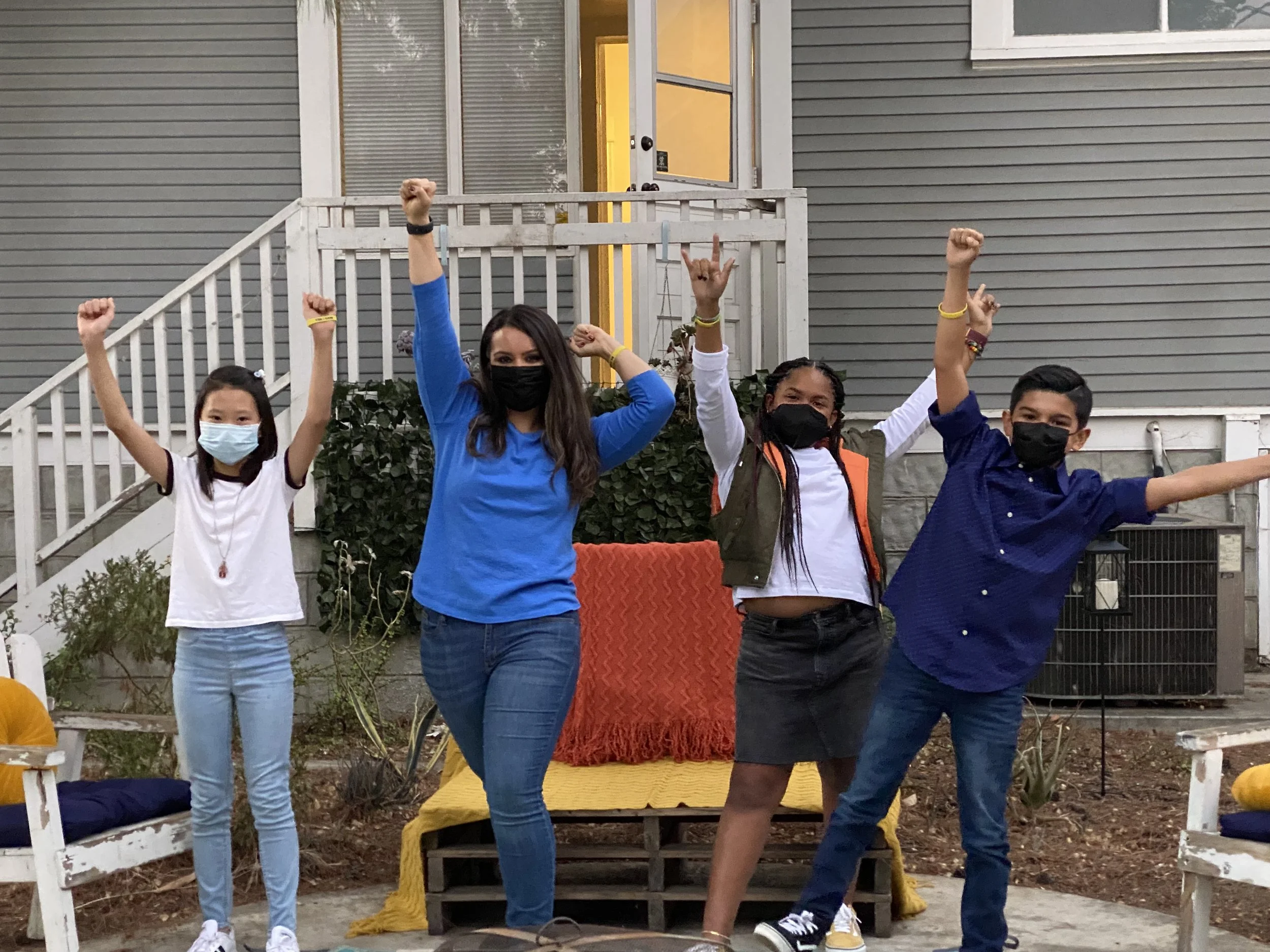 Lisa Moe and a group of students cheering with their arms raised outdoors