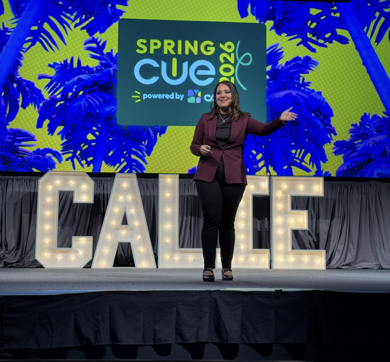 Lisa Moe delivering a keynote on the CALIE stage in front of giant lit-up CALIE letters and a Spring CUE 2026 screen.