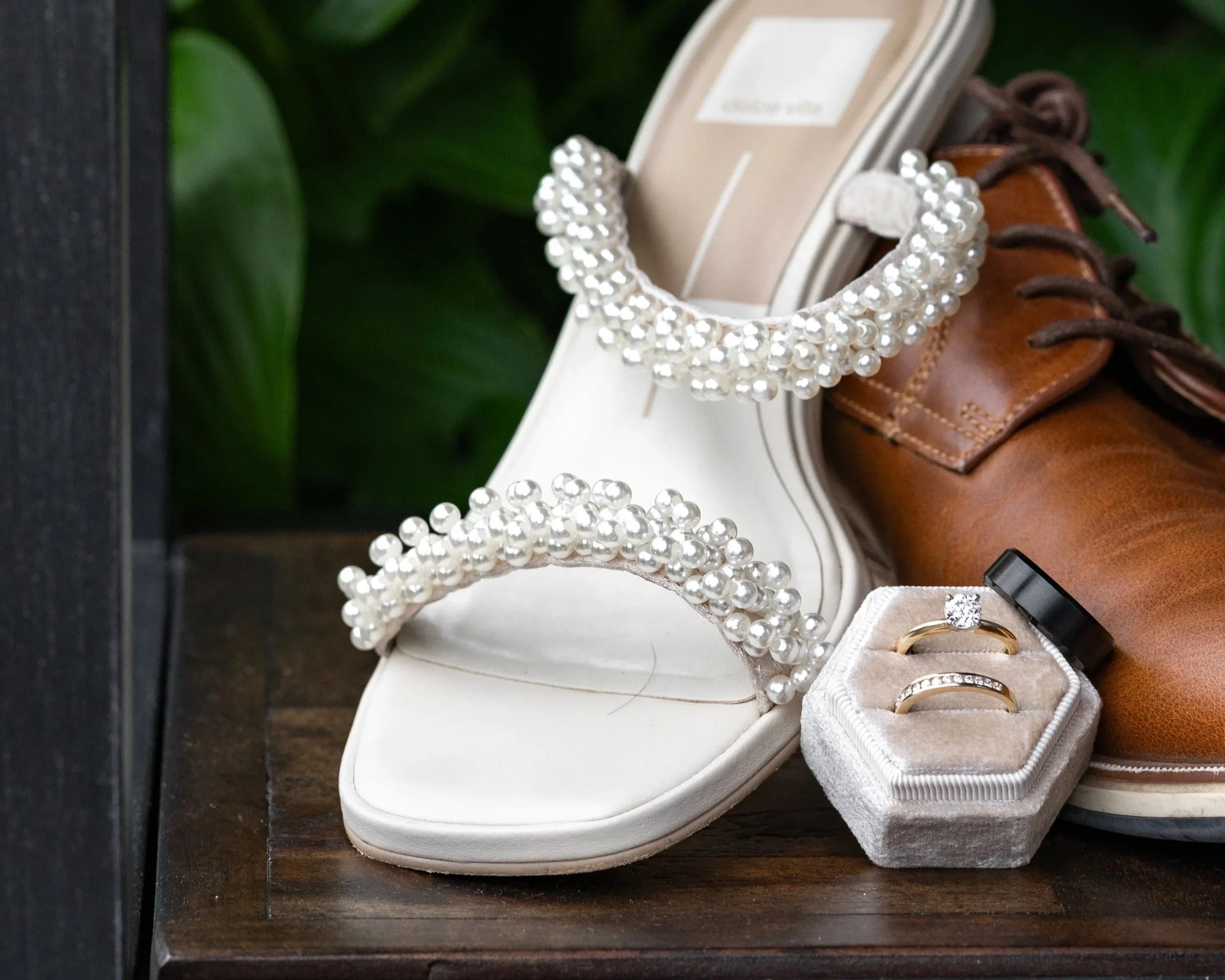 Fashion jewelry displayed at a store, including a pearl bracelet, rings, and a watch, alongside shoes and a jewelry box.