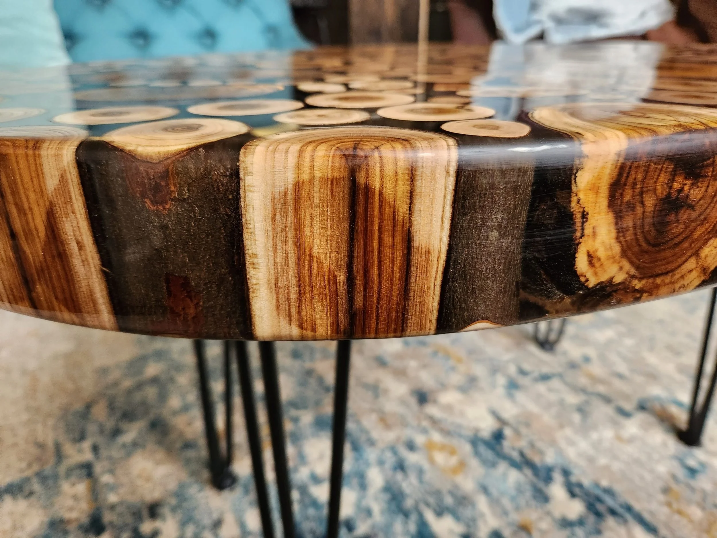 Close-up of a wooden table with a glass cover, revealing light and dark wood rings inside the table's surface.