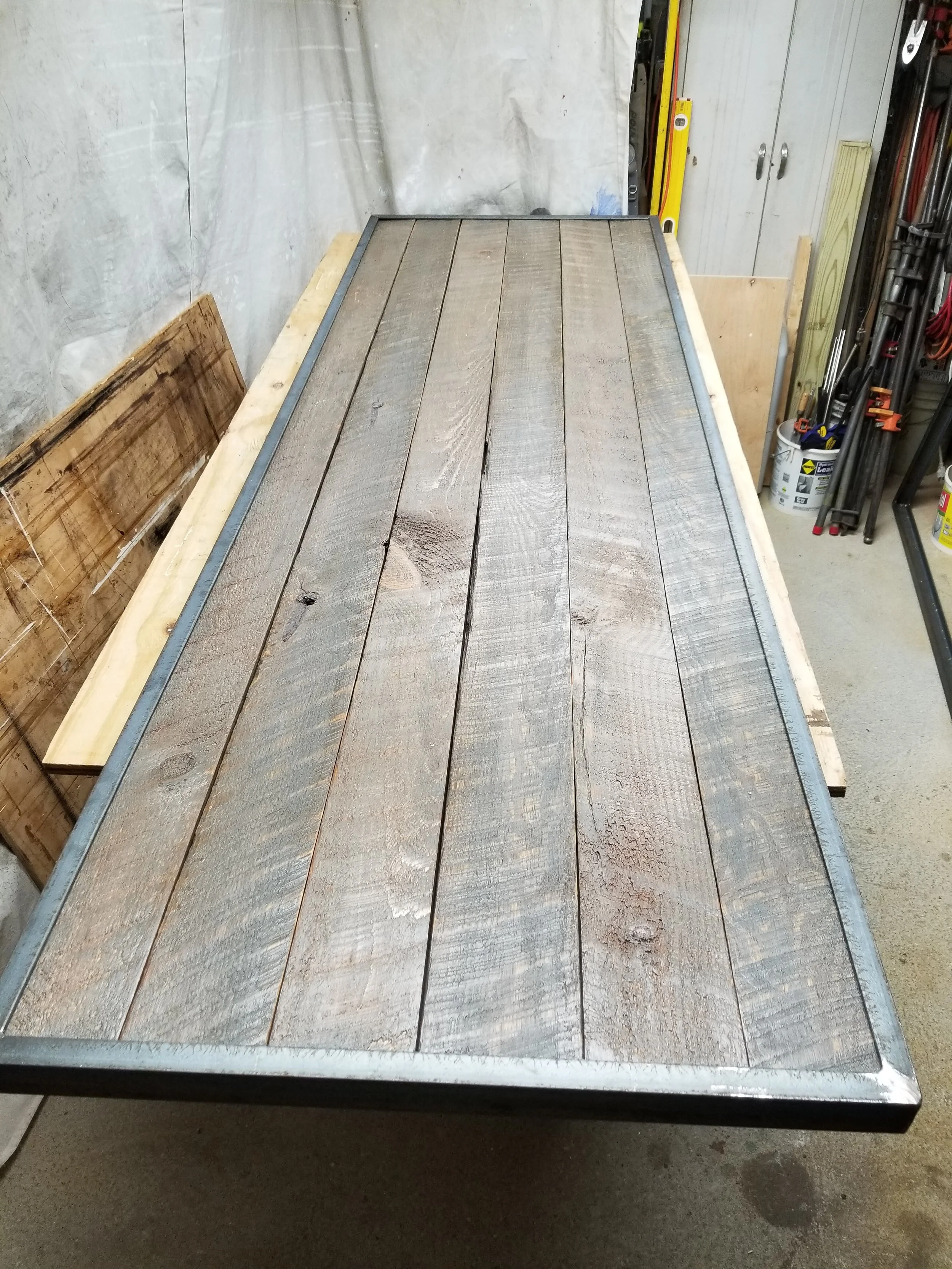 A workbench with wooden planks, a metal frame, and various tools in a workshop setting.