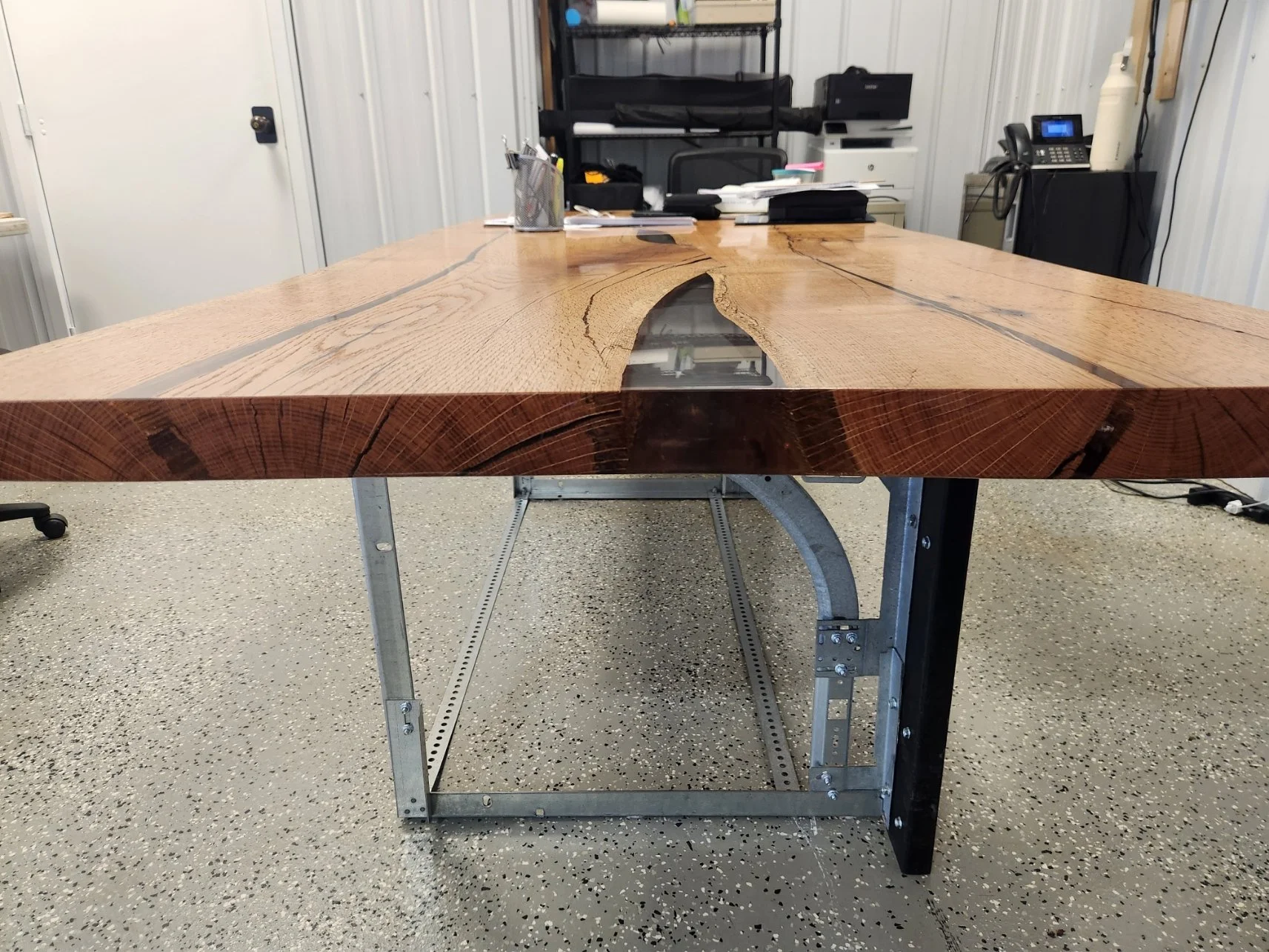 A custom-made wooden conference table with a live edge, placed on a custom metal table stand in conference room at Interstate Garage Doors Inc.