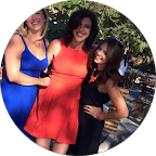 Three women standing outdoors in a park, smiling, dressed in colorful outfits