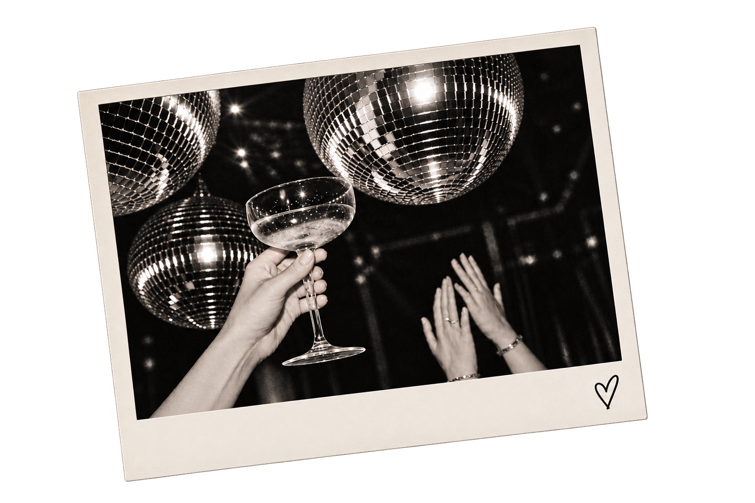 A person holding a champagne coupe glass in front of disco balls and hands raised in celebration, with a small heart drawn on the photo's border.