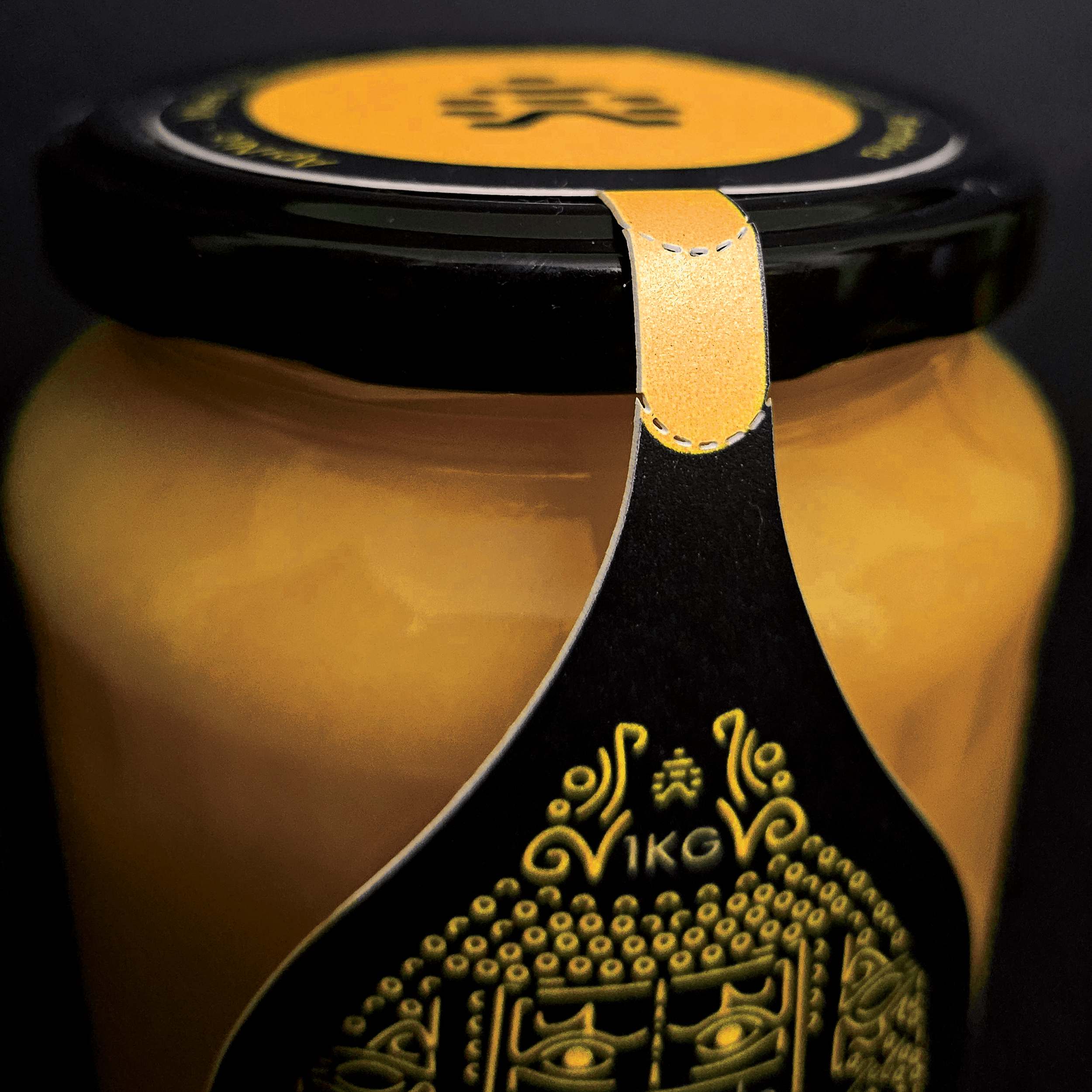 Close-up of a black and yellow wristwatch with a round face, featuring a visible gear mechanism underneath the transparent cover, and yellow stitching on the black strap.
