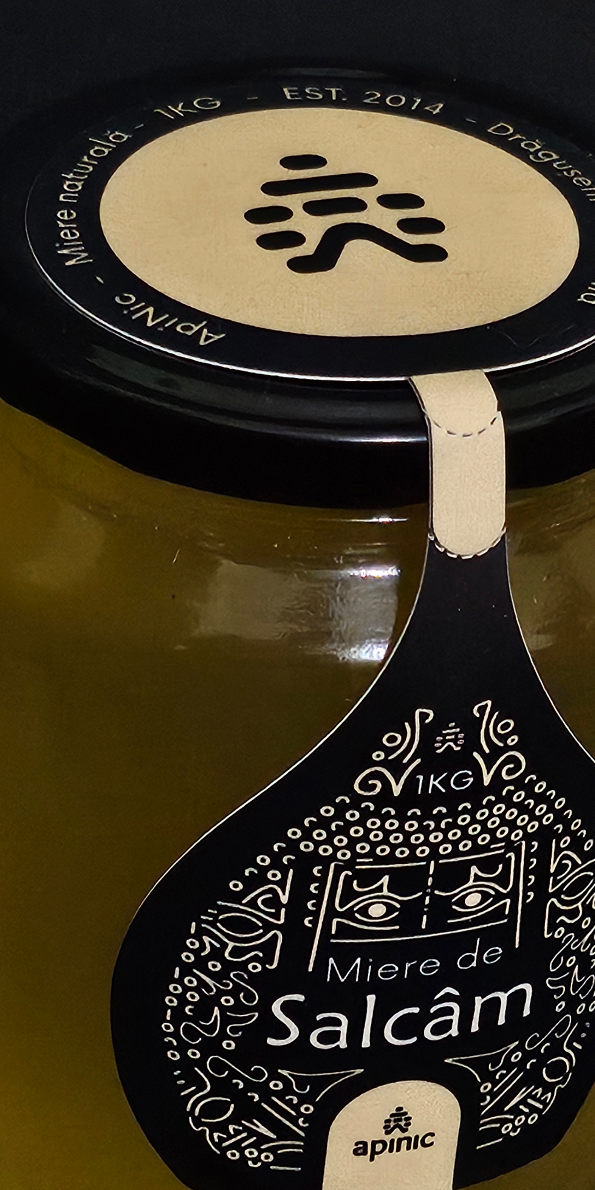 Close-up of a black container lid with a beige label printed with a black stylized fish icon and the text "Mięso de Salcâm". The lid is on a metallic surface, with a pull tab visible.
