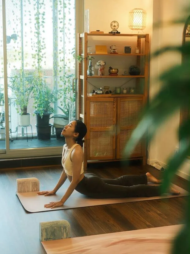 Student in cobra pose, lit by the window