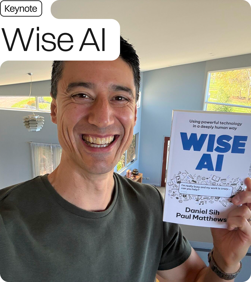 Daniel Sih is smiling and wearing a grey top. He is holding his book 'Wise AI'