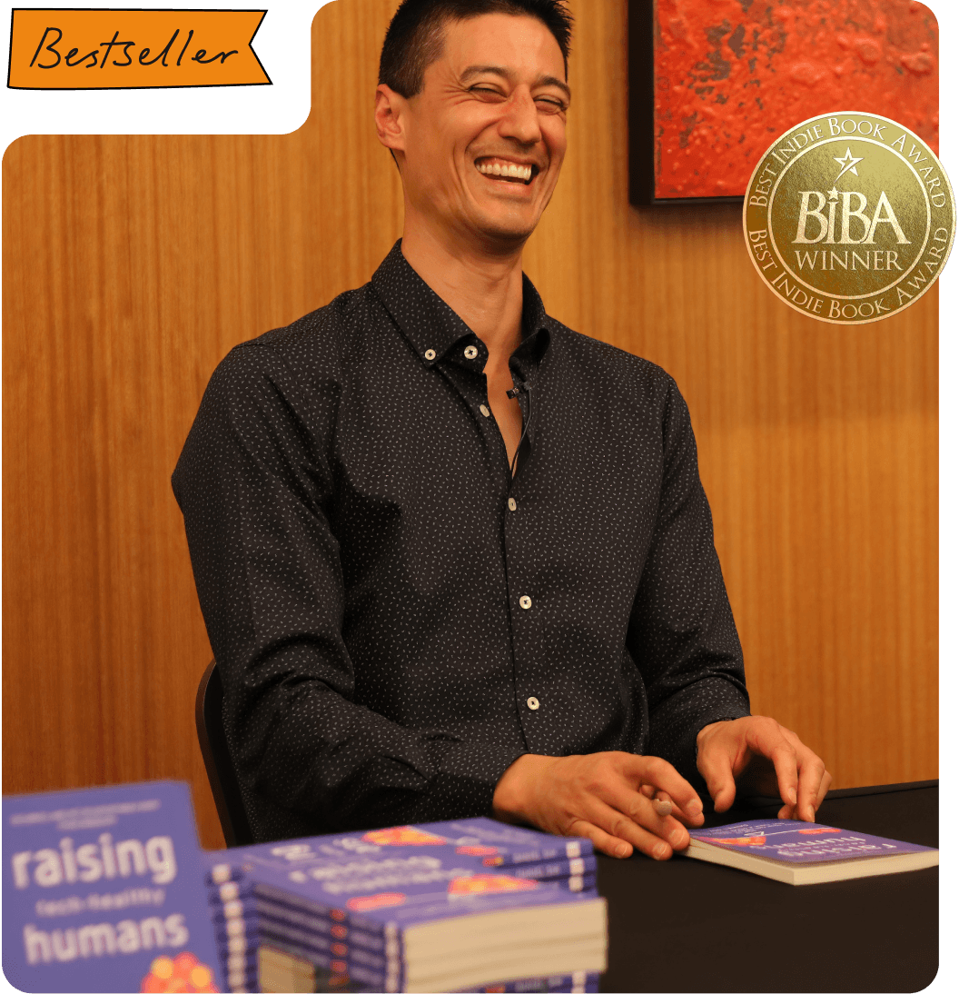 Daniel sitting and smiling as he signs his book 'Raising Tech-Healthy Humans'