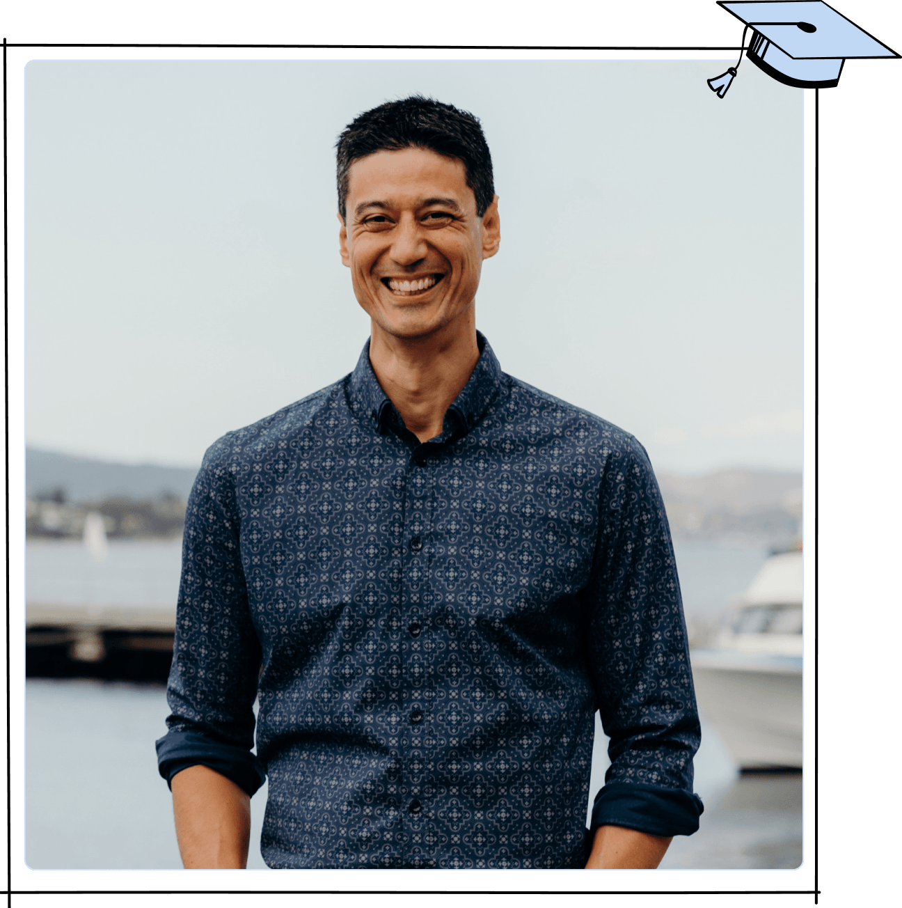 A portrait of Daniel Sih outside on a pier in Tasmania. He wears a patterned blue shirt.