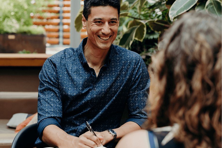 Daniel Sih sits across from a woman as he talks and smiles